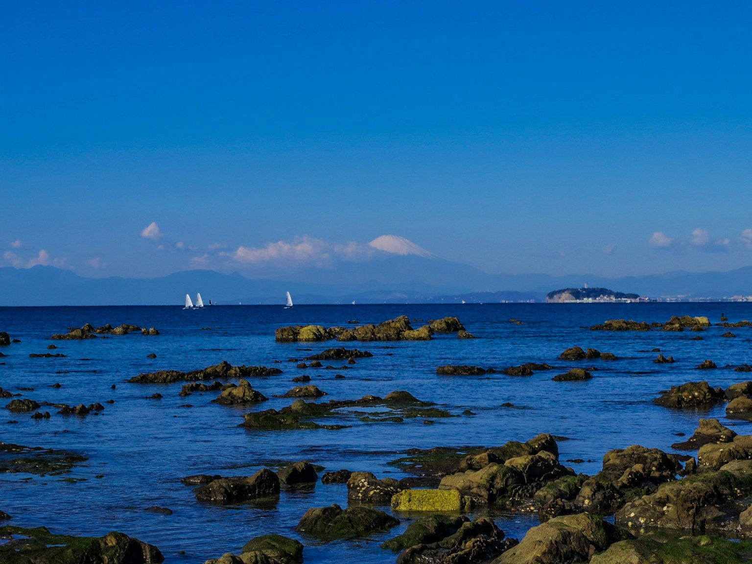 蓝色海洋与岩石海岸和白色帆船的风景