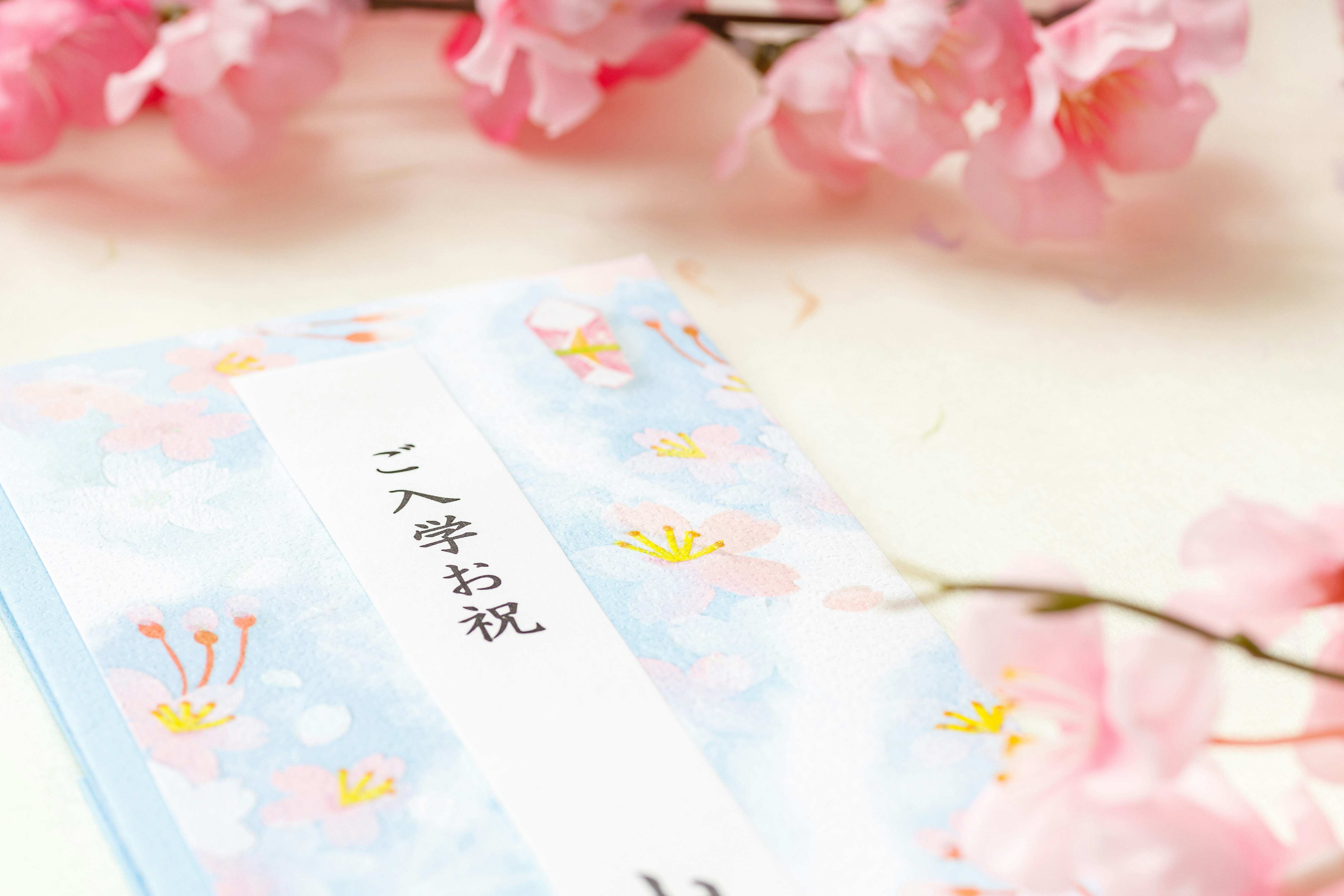 桜の花びらと入学祝いのご祝儀袋が並ぶシーン