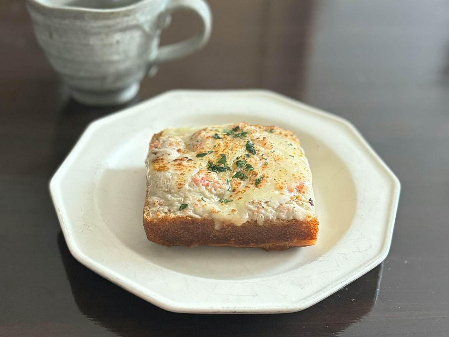Getoastetes Brot auf einem weißen Teller mit einer Kaffeetasse im Hintergrund