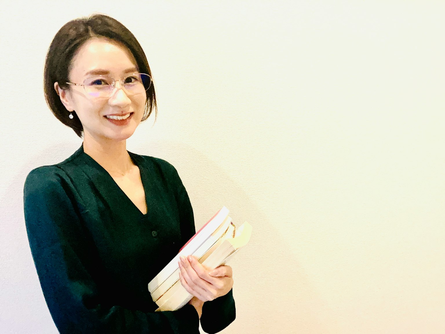 Một người phụ nữ mỉm cười khi cầm sách trước nền đơn giản