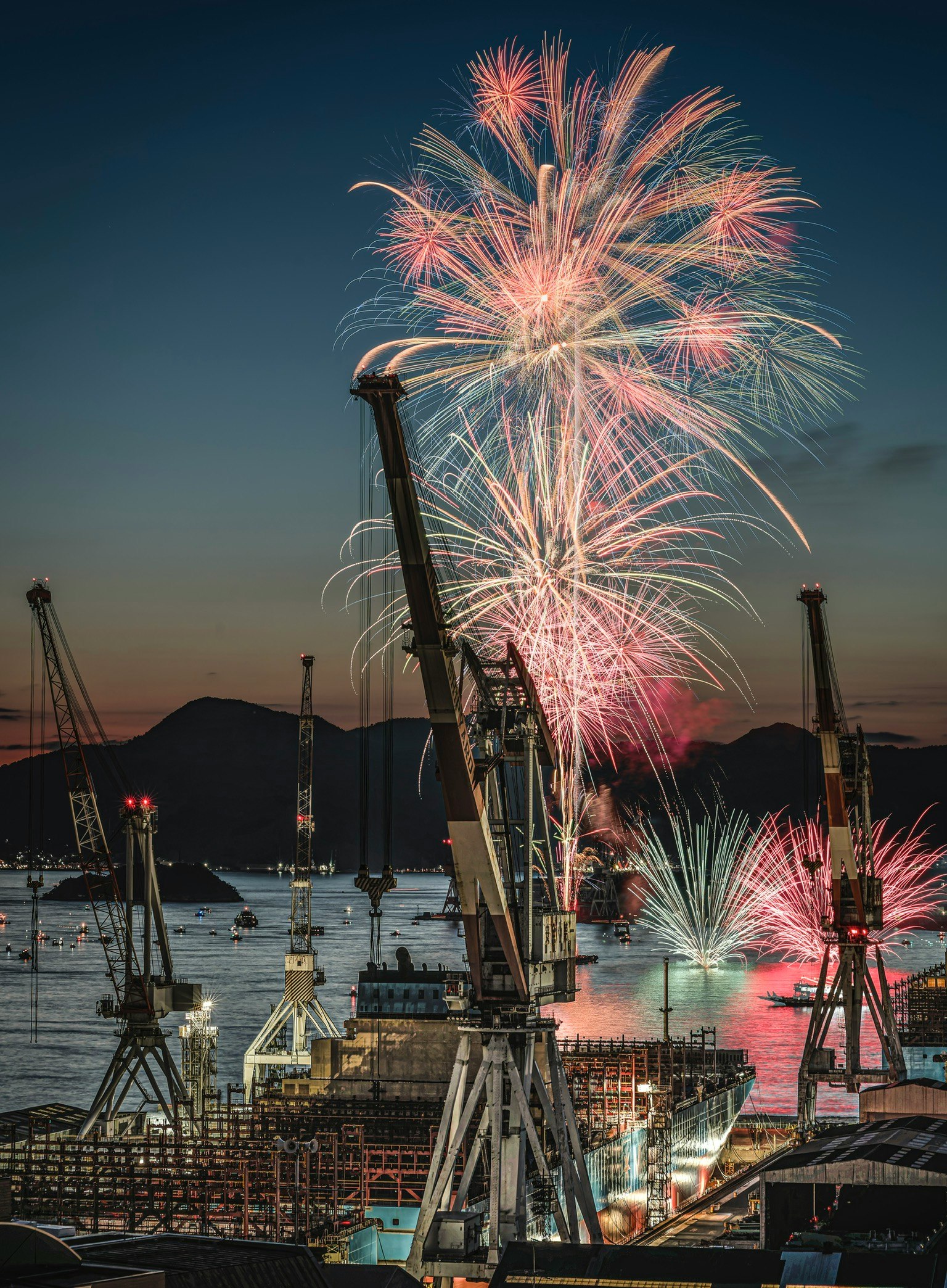 呉の夏祭り 海上花火大会の造船所クレーンと海上花火の夜景