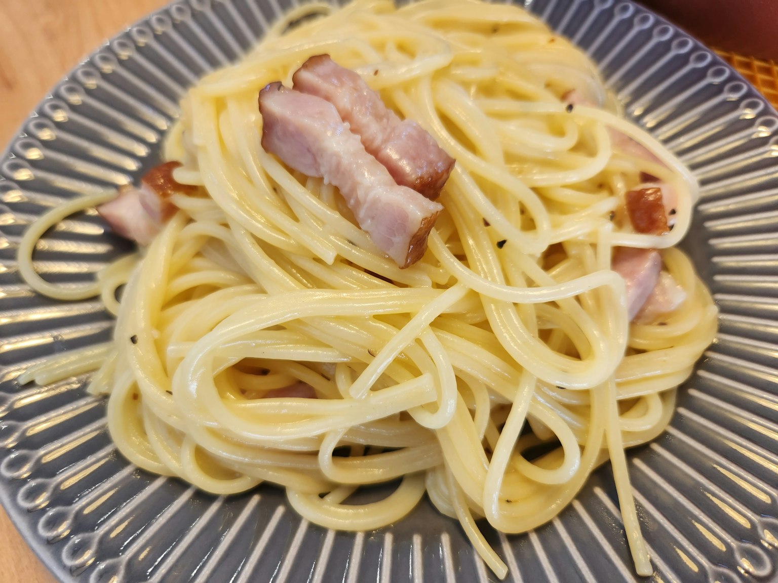 Spaghetti dengan saus krim yang ditambah irisan daging babi