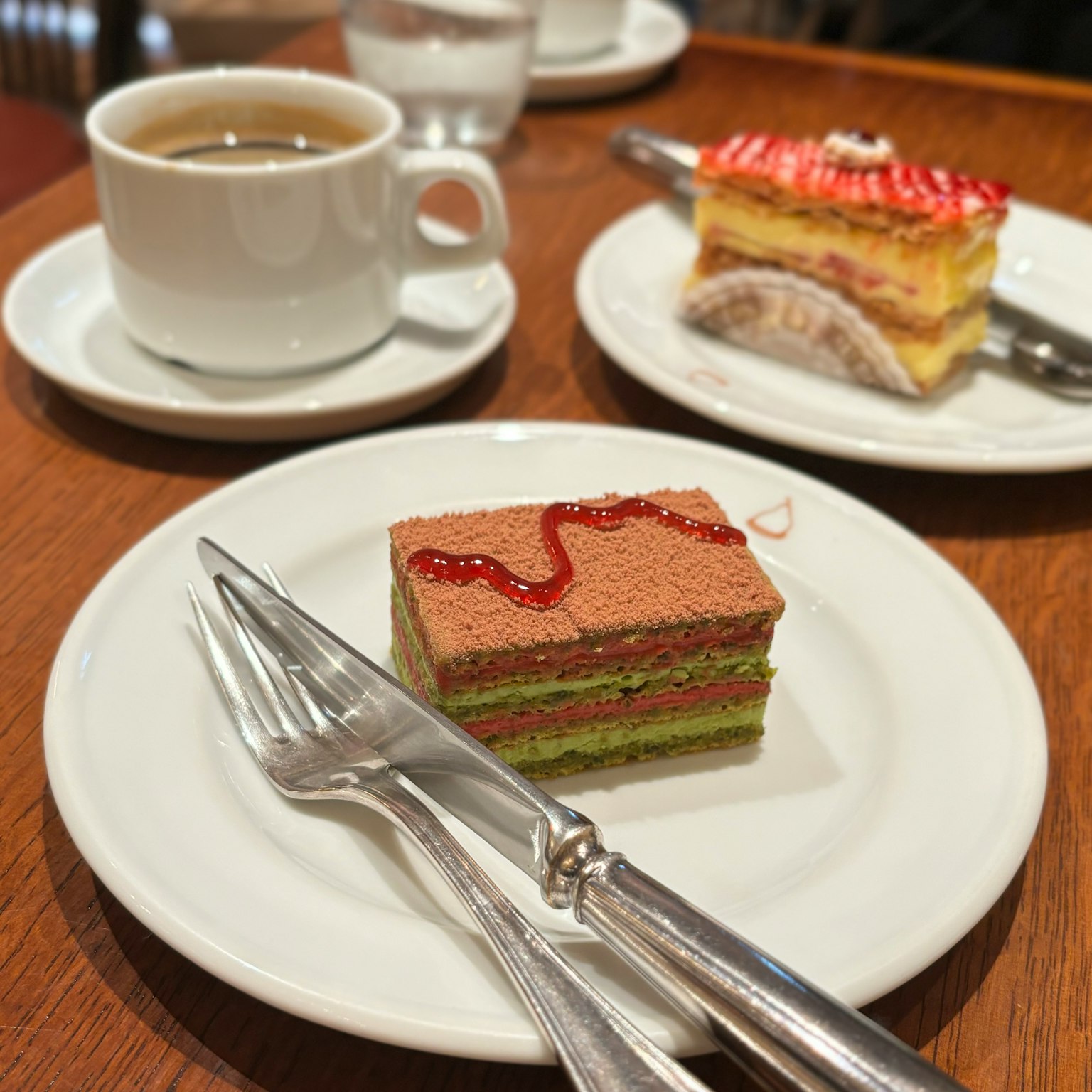 Un tavolo con una tazza di caffè e due dolci colorati