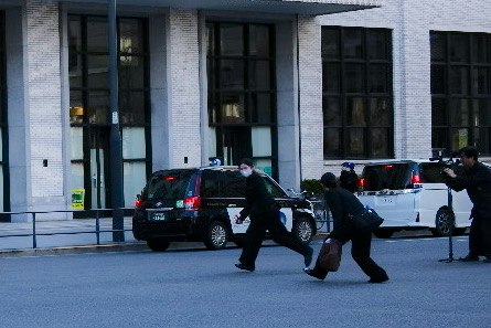 escena de sesión de fotos de boda con personas moviéndose frente a un edificio