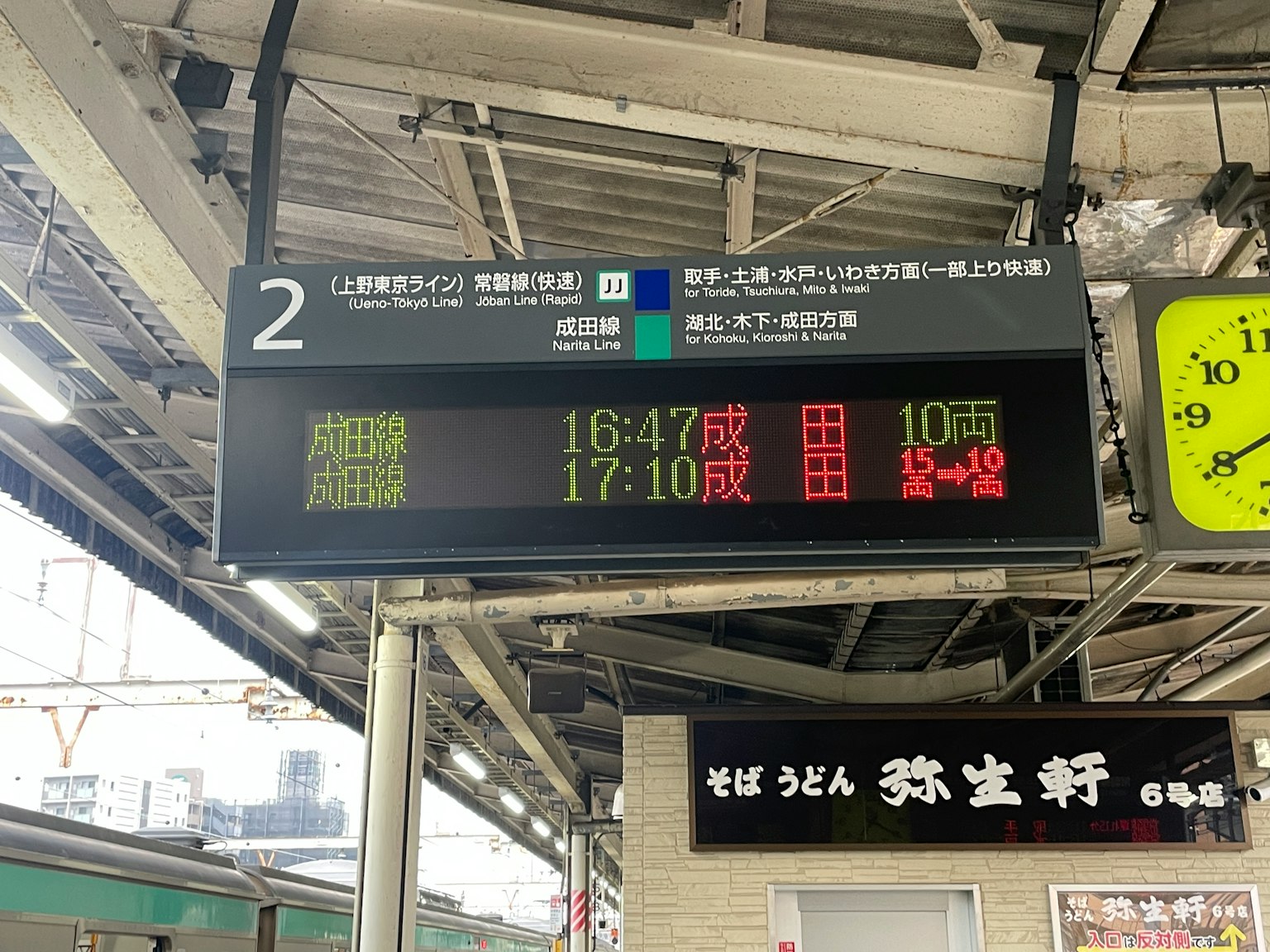 Panneau d'affichage électronique dans une gare montrant les horaires des trains et une horloge