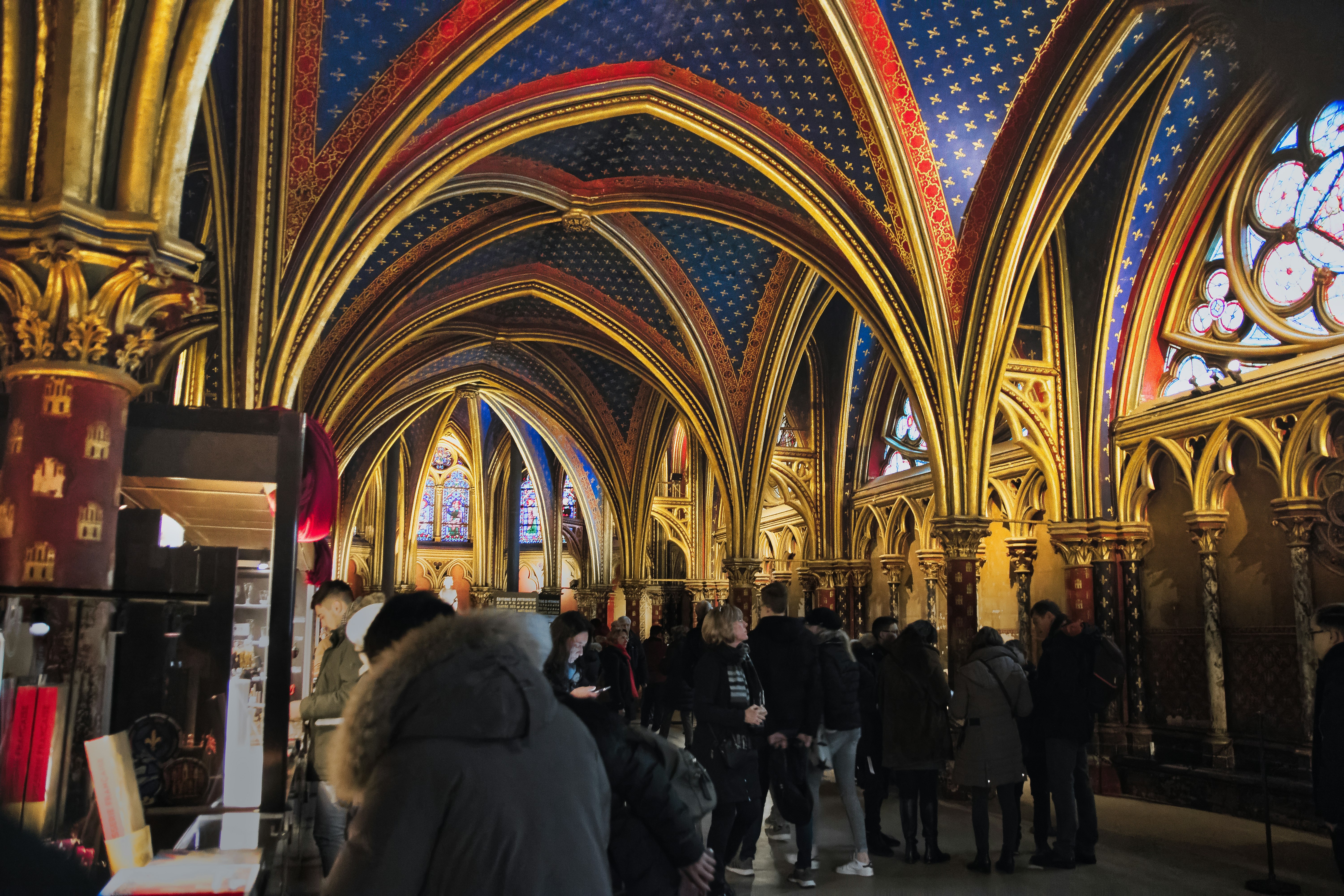 People walking through a cathedral arcade with arched ceiling and stained glass