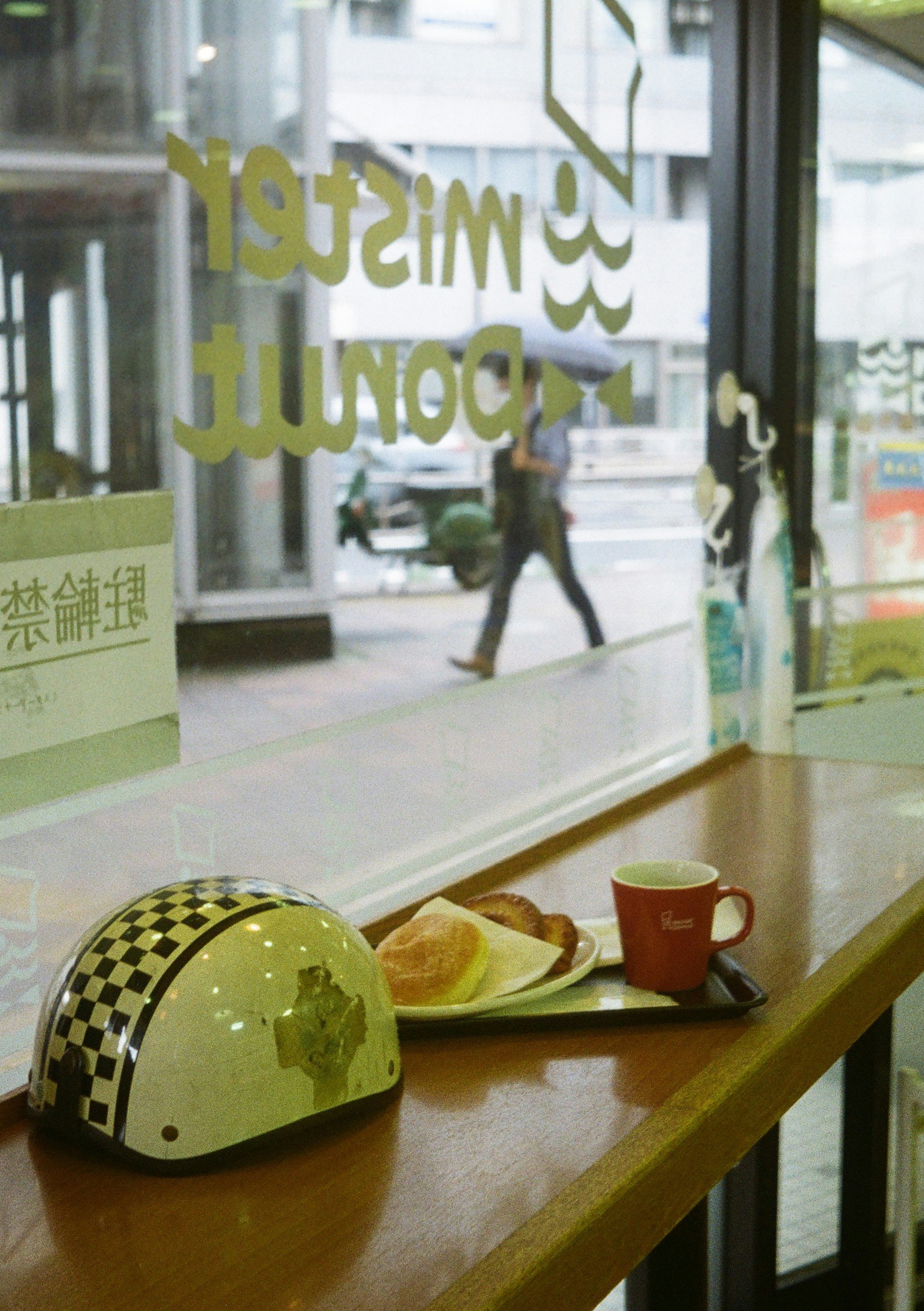 雨の店内窓辺でヘルメットと朝食トレー