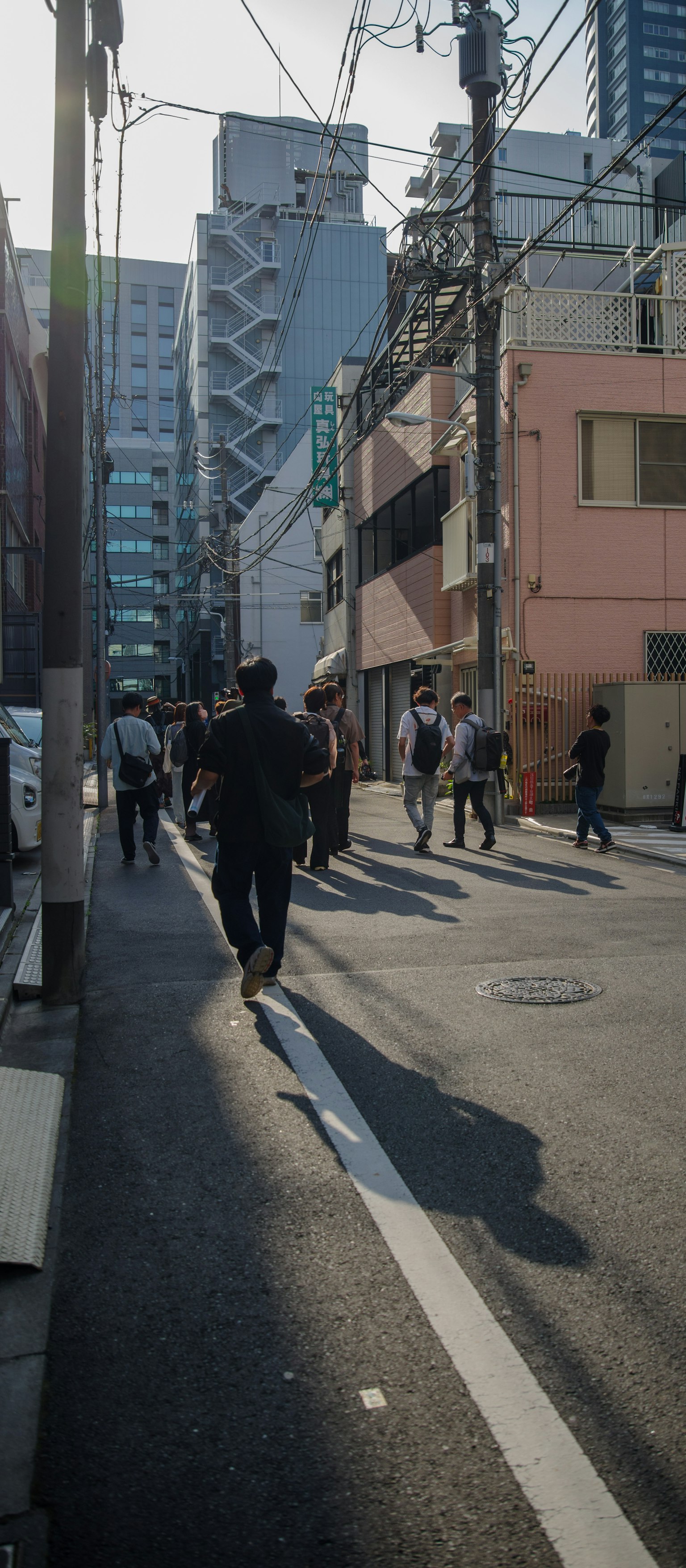 Escena urbana con personas caminando por la calle edificios y líneas eléctricas visibles