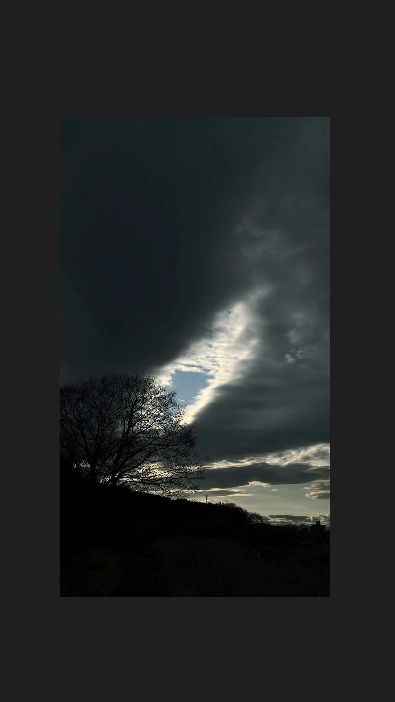 Winterdämmerung mit blauem Himmel zwischen Wolken und Lichtstrahl