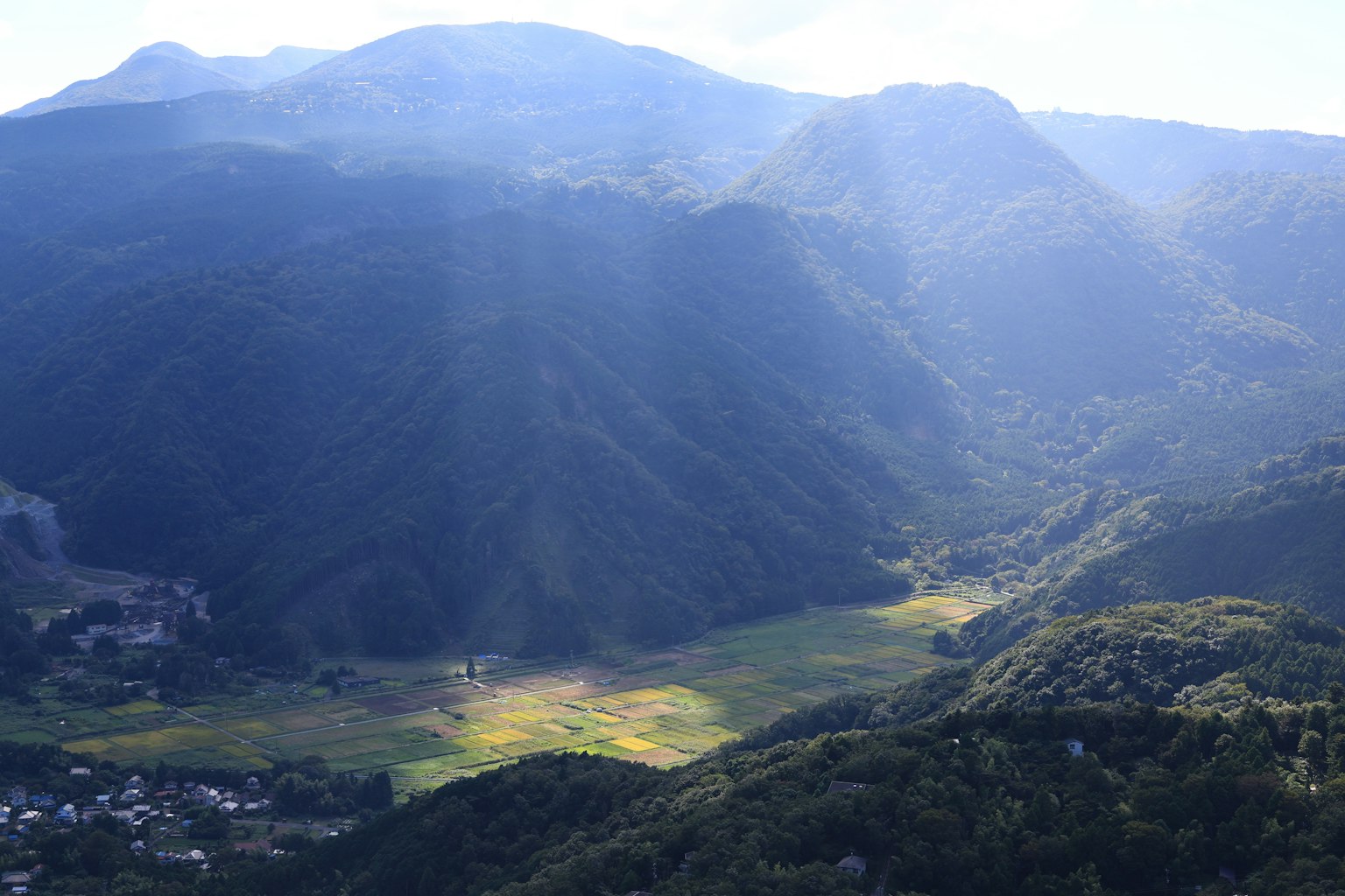 阳光透过的绿色山谷和周围的山脉风景
