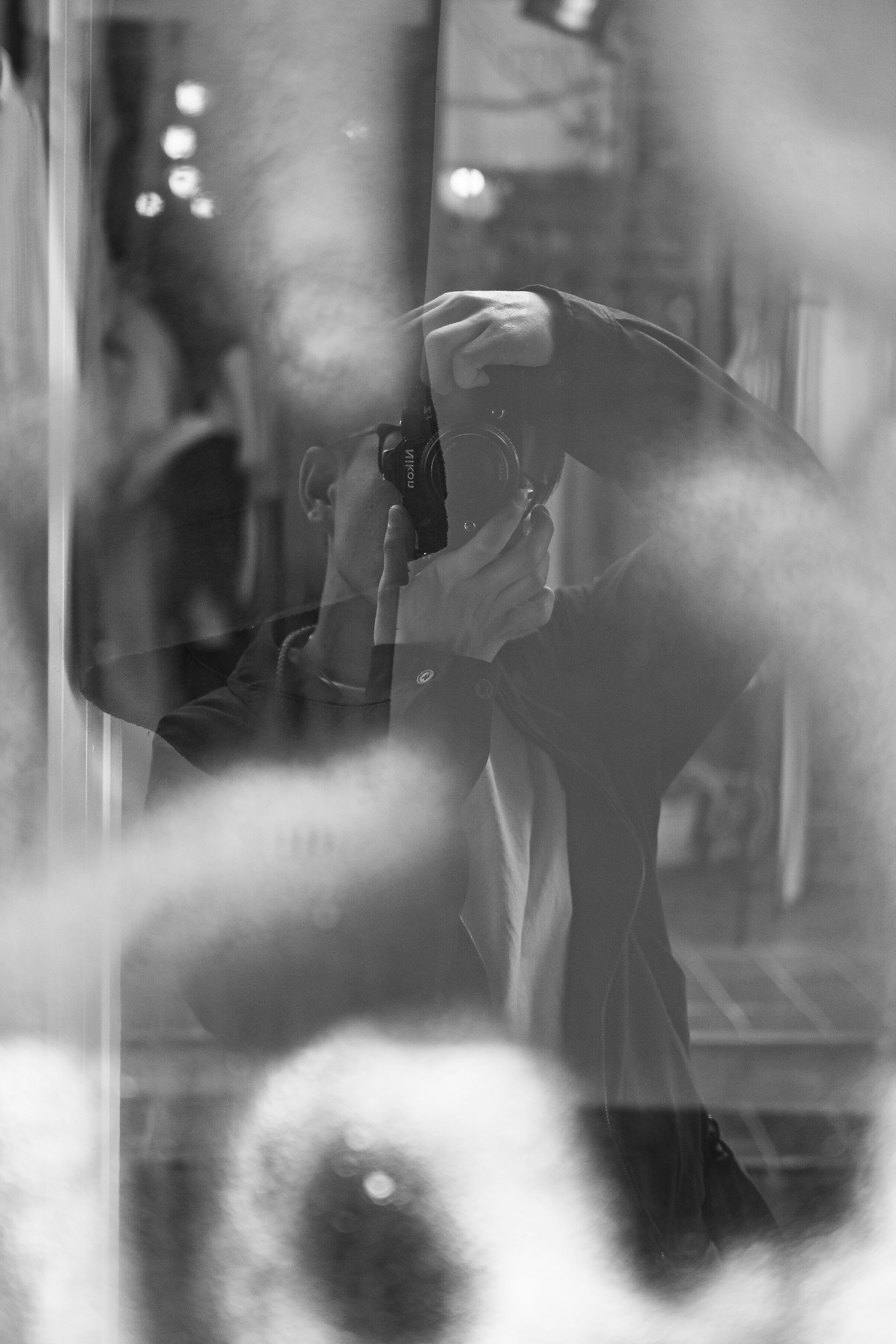 Foto en blanco y negro que muestra a una persona a través del vidrio con un abrigo