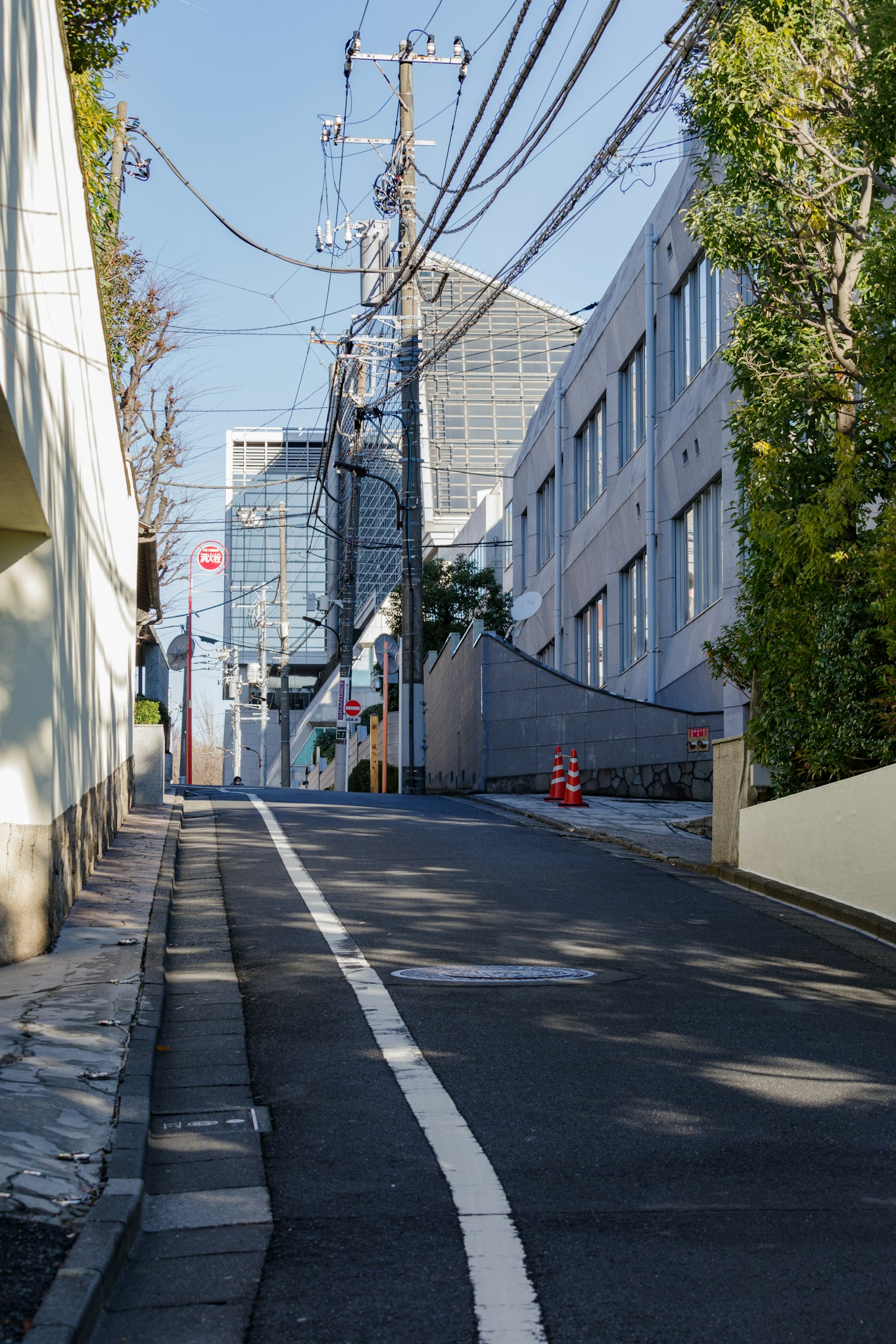 Rue en pente avec des bâtiments modernes et des poteaux électriques