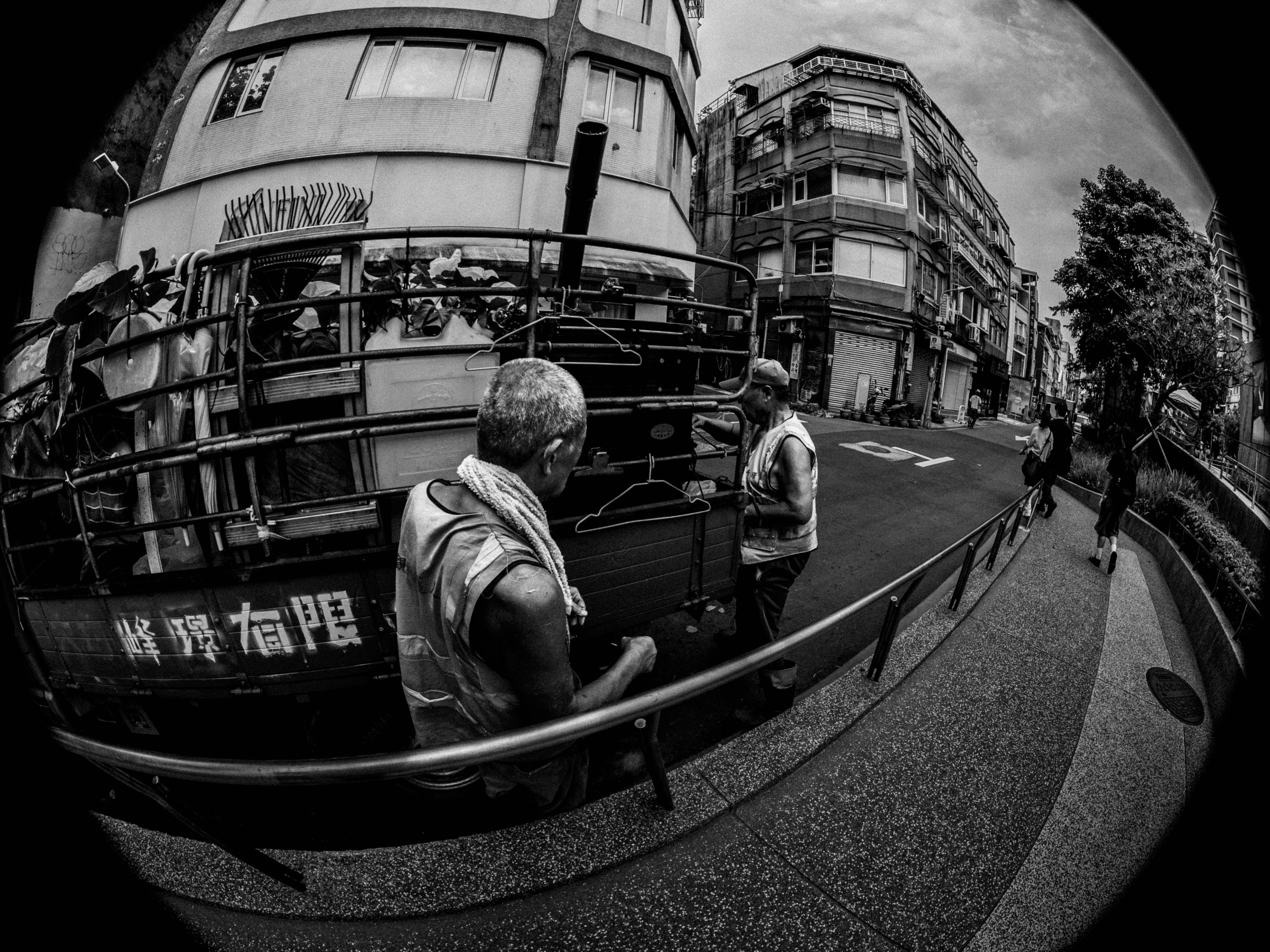 路地のバス停付近で人が見つめる街並み
