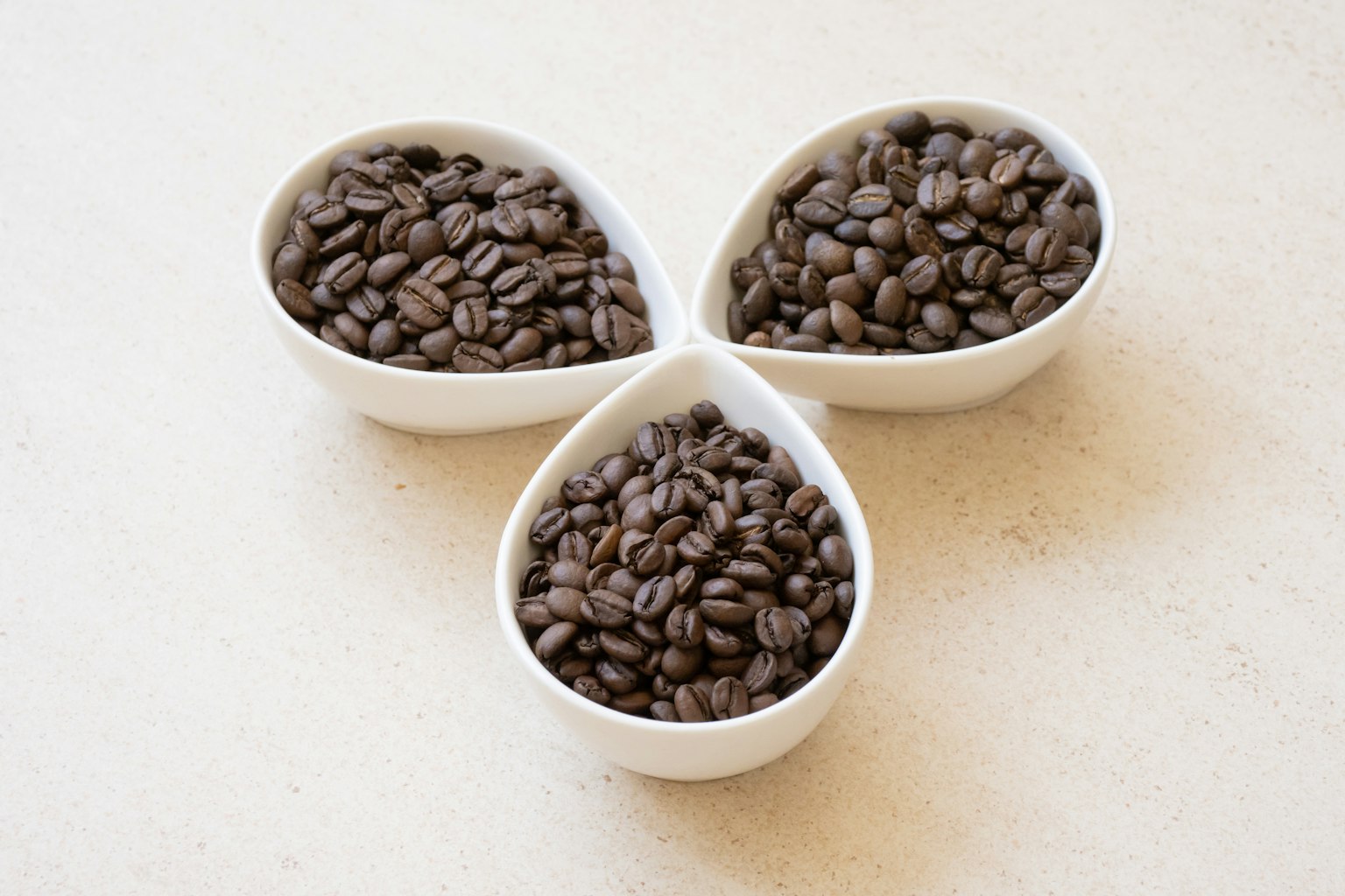 Immagine di chicchi di caffè in tre ciotole bianche