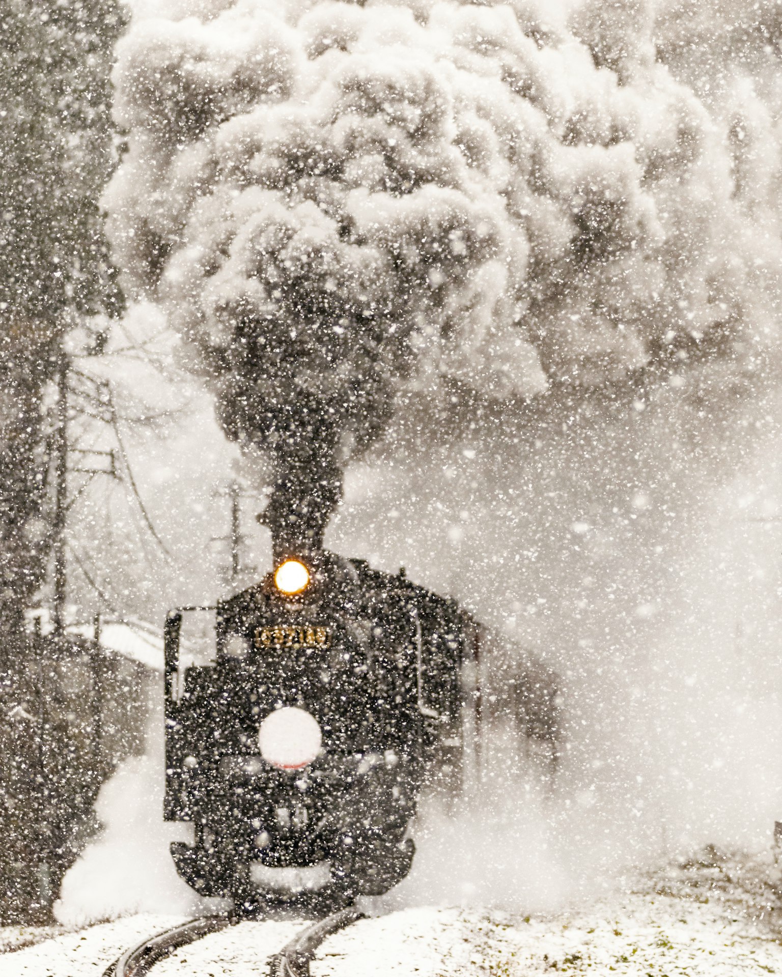 Locomotiva a vapore che viaggia nella neve con fumi