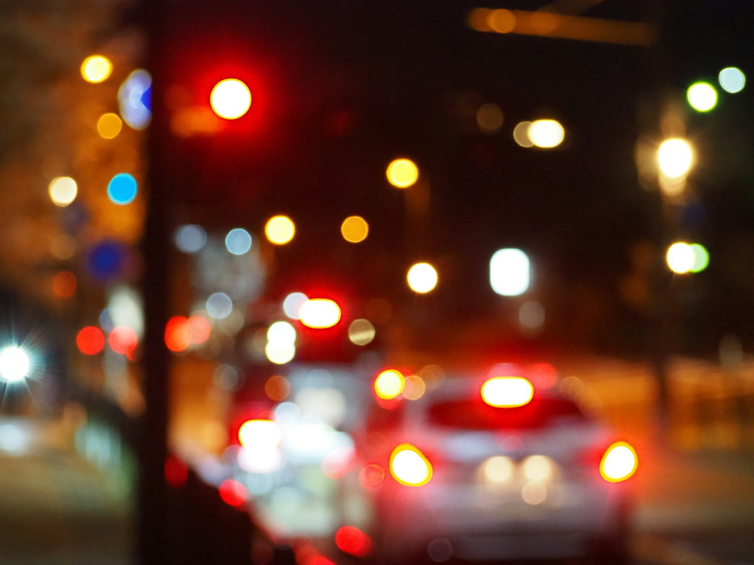 Luci del traffico notturno sfocate con luci posteriori delle auto