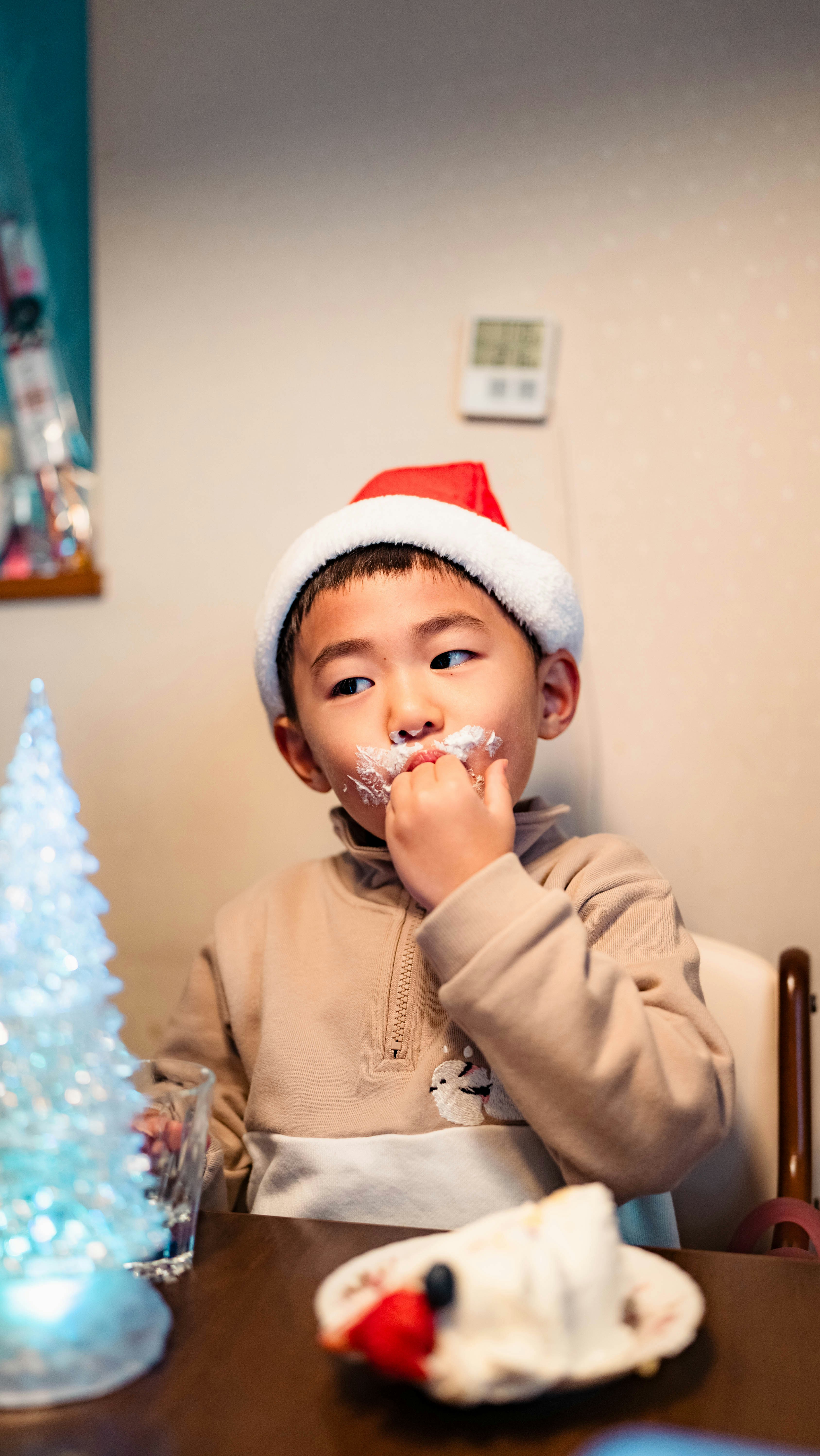 Indoor moment of a child wearing a Santa hat eating sweets at a table