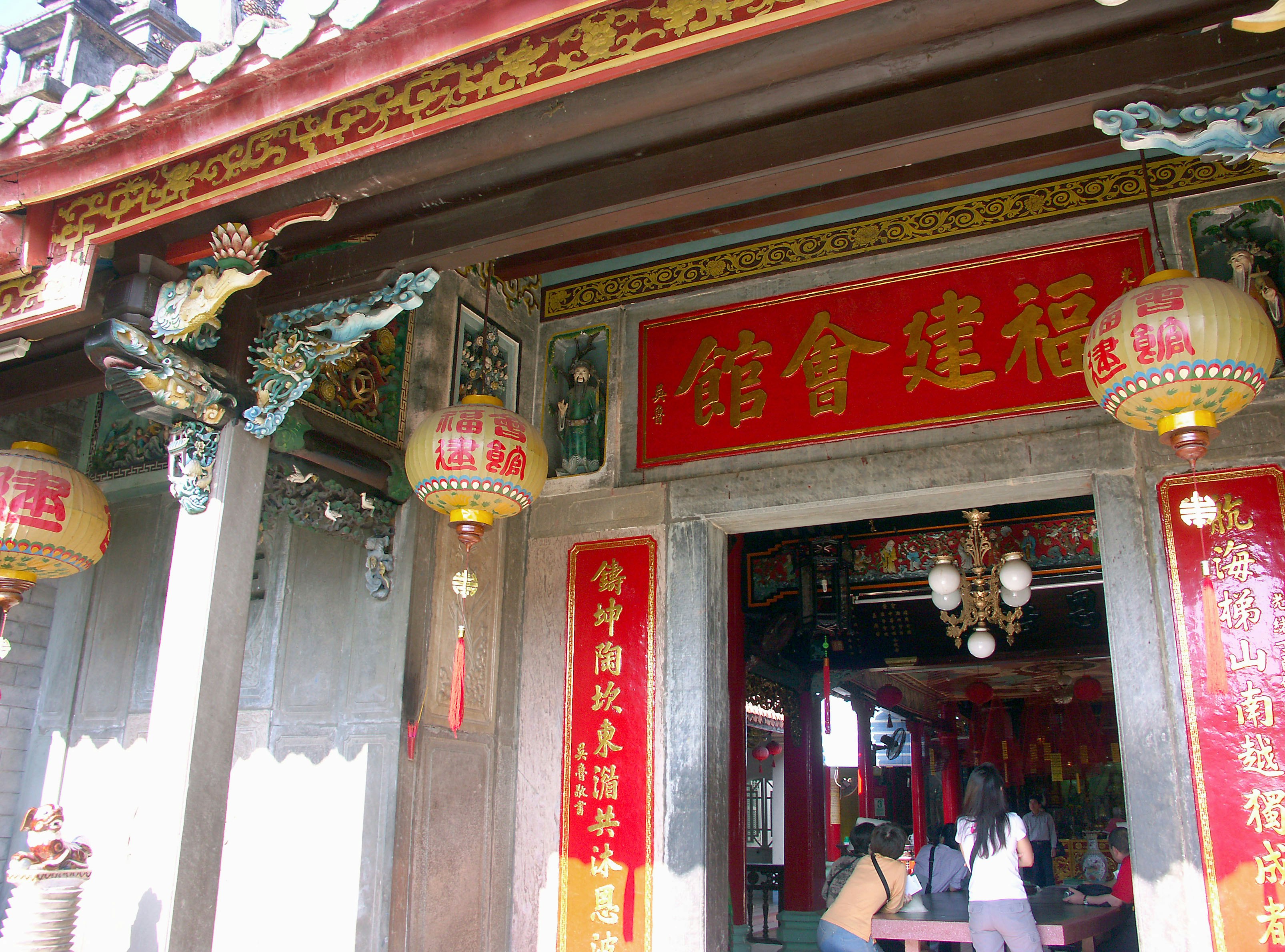 Entrance of a traditional temple featuring red signs and decorative lanterns