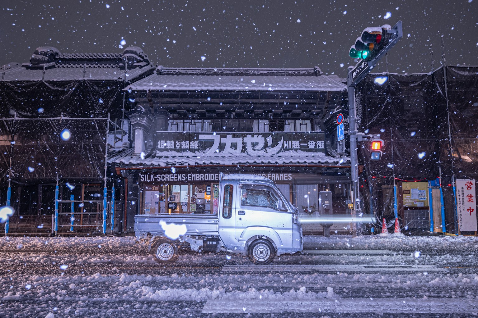 雪中行驶的小型卡车与背景中的传统建筑在夜晚