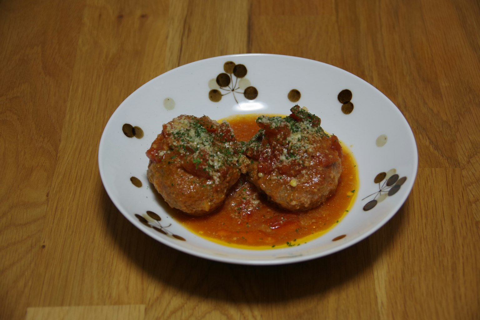 Deux boulettes de viande dans une sauce tomate garnies d'herbes sur une assiette décorative