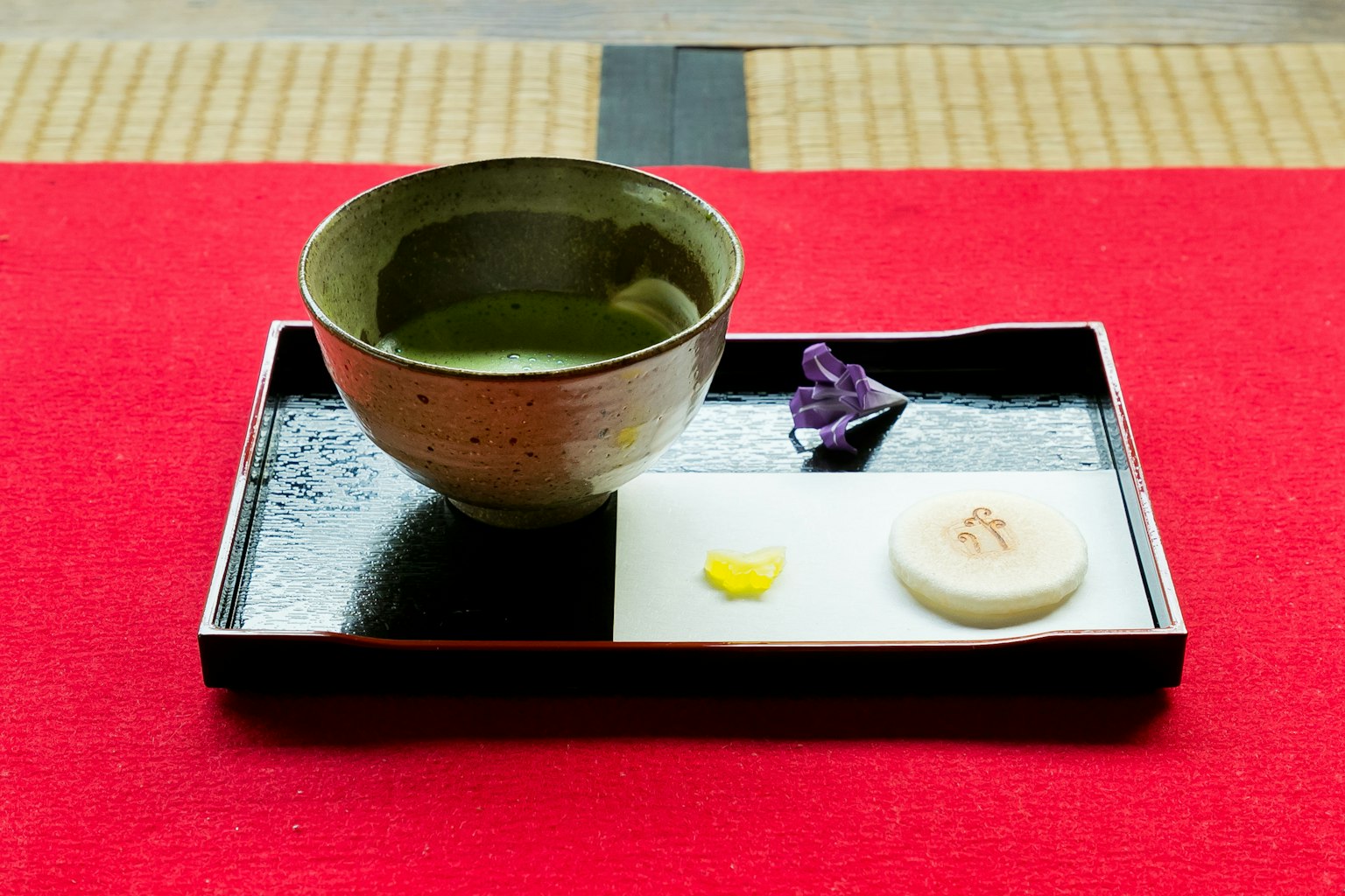 Thé matcha servi dans un bol avec des douceurs japonaises traditionnelles sur un plateau noir