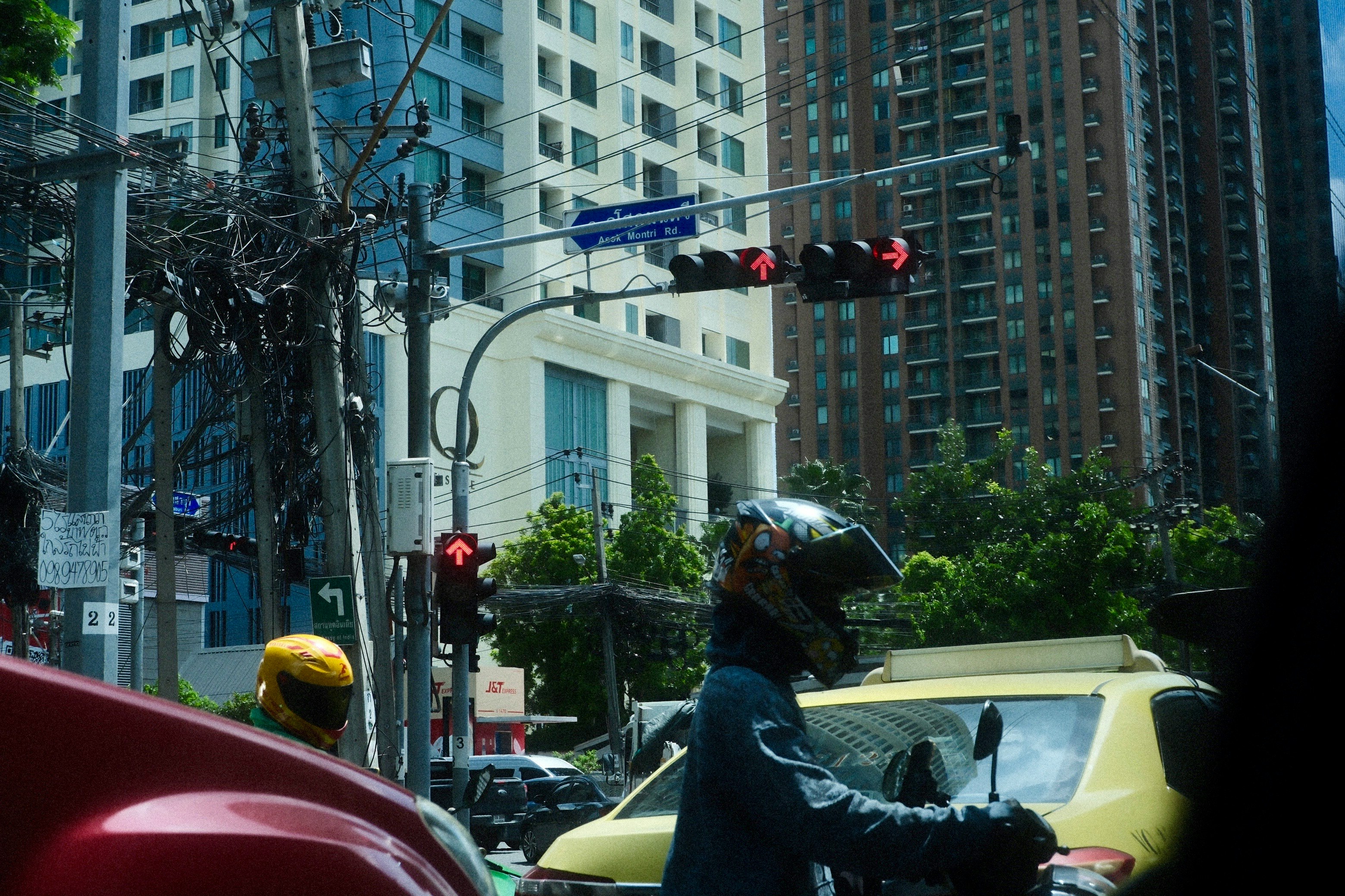 motorbike and cars waiting at a city intersection with tall buildings