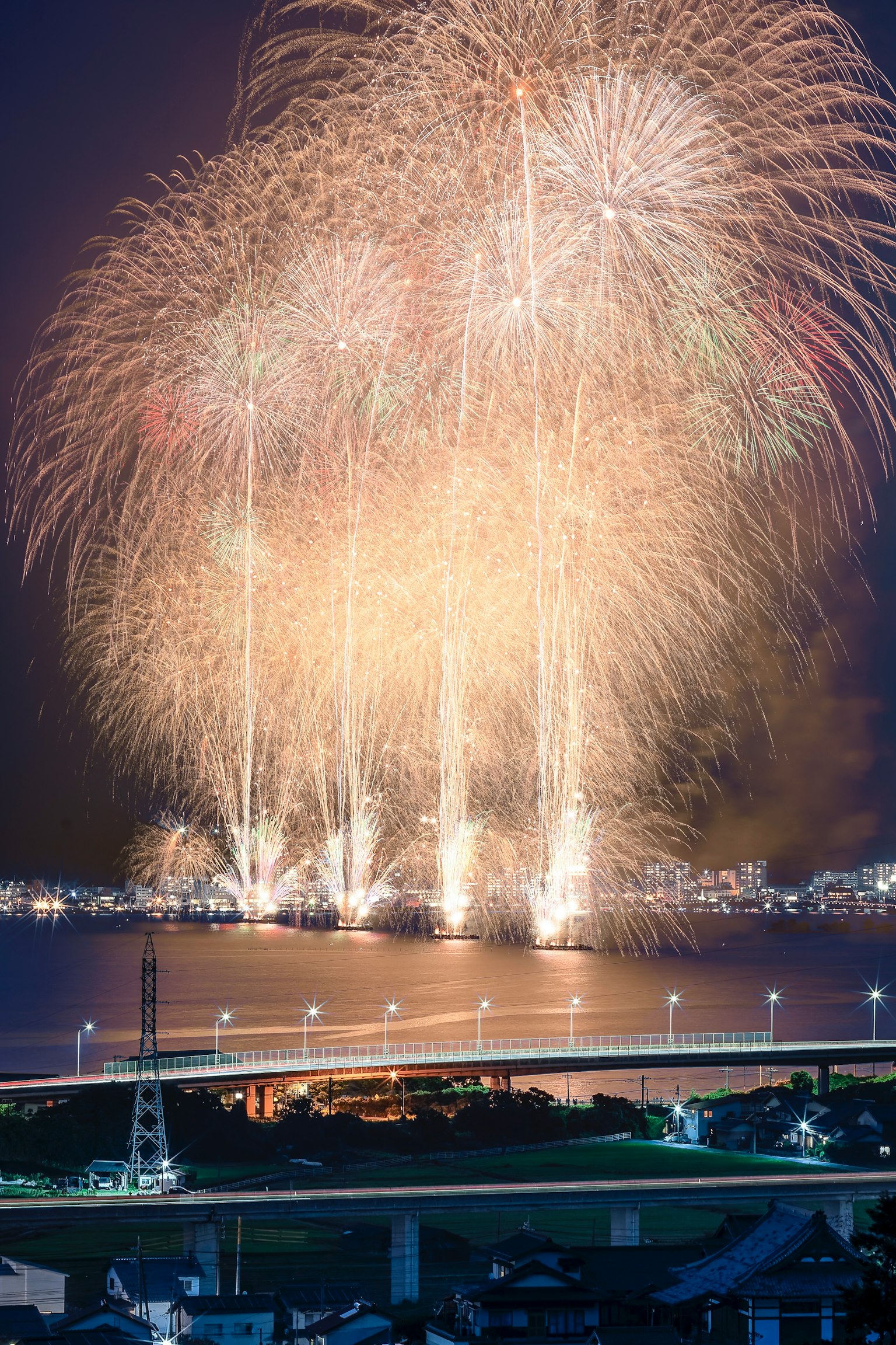 Un bellissimo spettacolo di fuochi d'artificio che illumina il cielo notturno riflesso sull'acqua