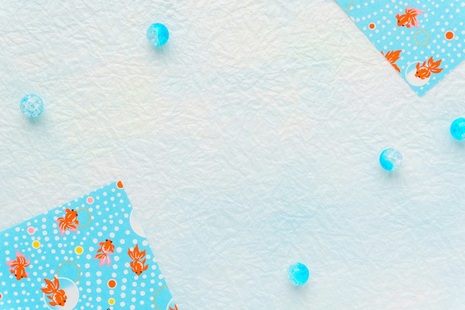 Blauer Hintergrund mit blumenmuster Papierstücken und verstreuten transparenten Perlen