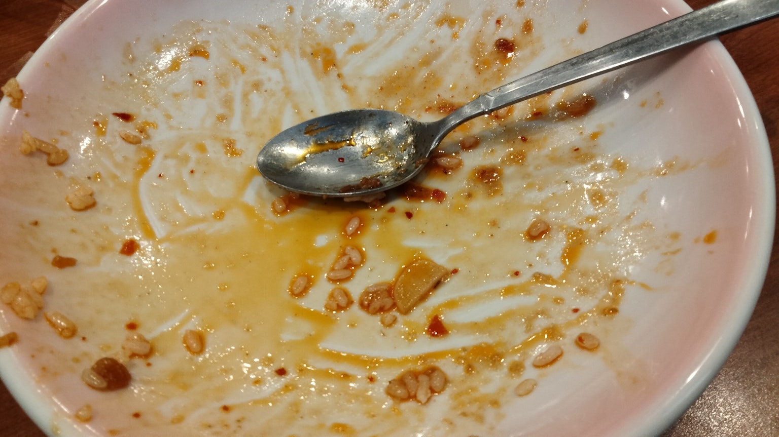 Plato vacío con migajas de comida y una cuchara