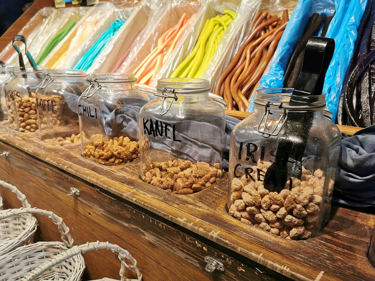 Glass jars filled with sweets displayed in a shop with colorful candy in the background