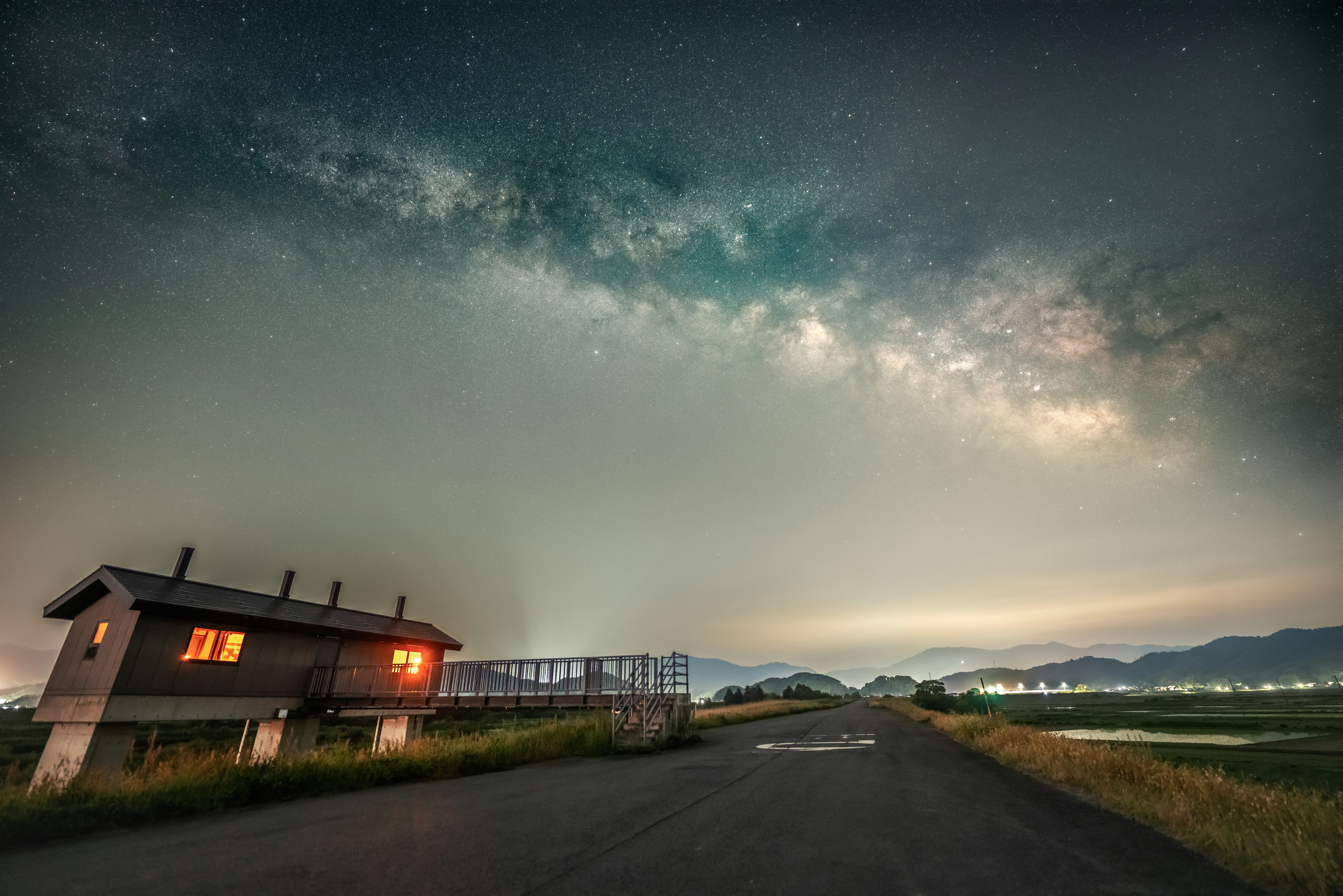 夜空に天の川が広がる田舎道と家の外観