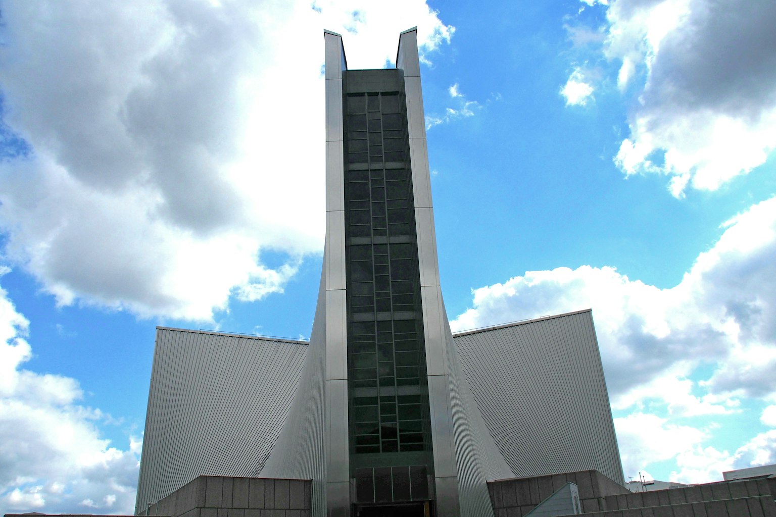 Vista esterna di un edificio di chiesa moderno con una torre alta sotto un cielo blu