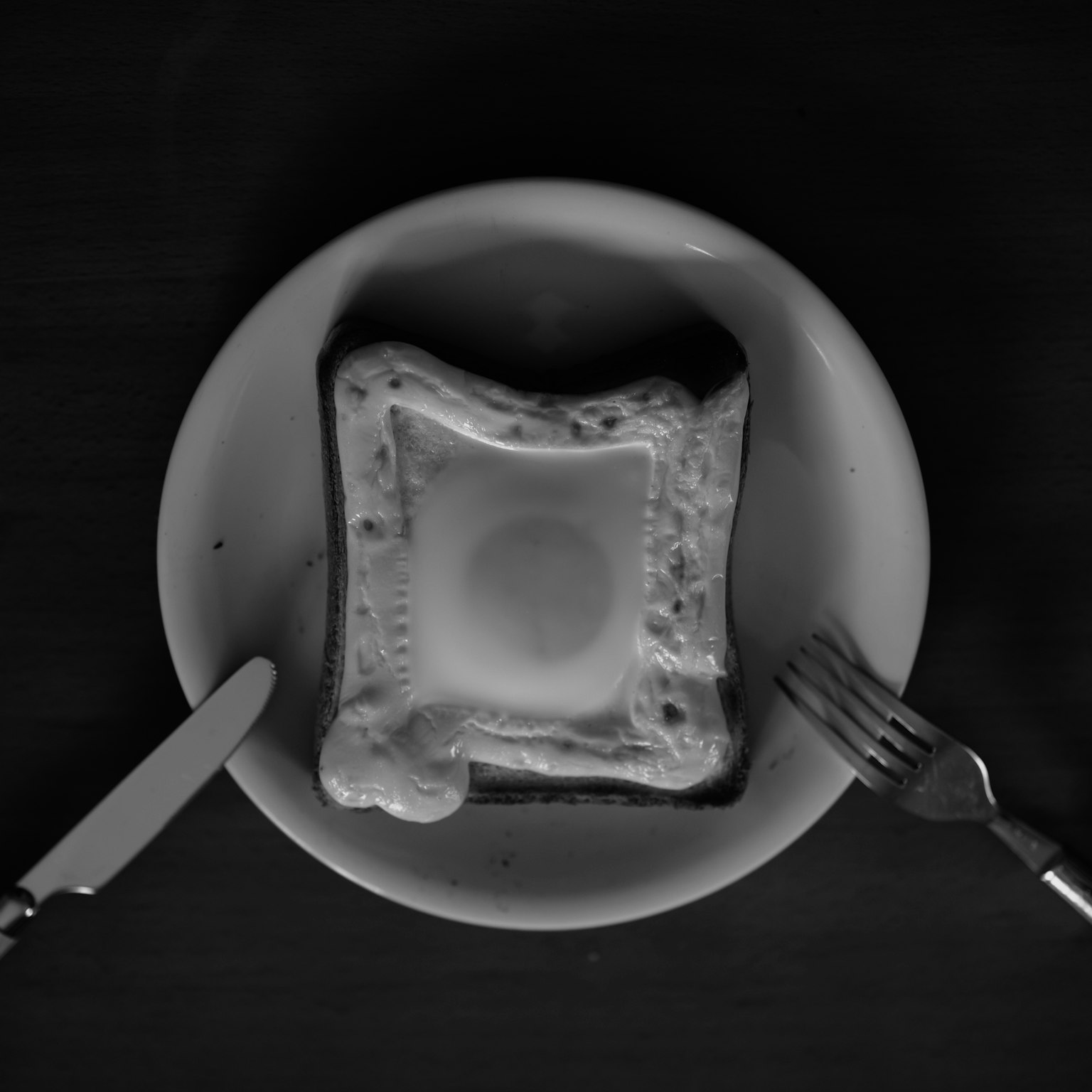 Tampilan atas roti panggang telur di piring hitam putih