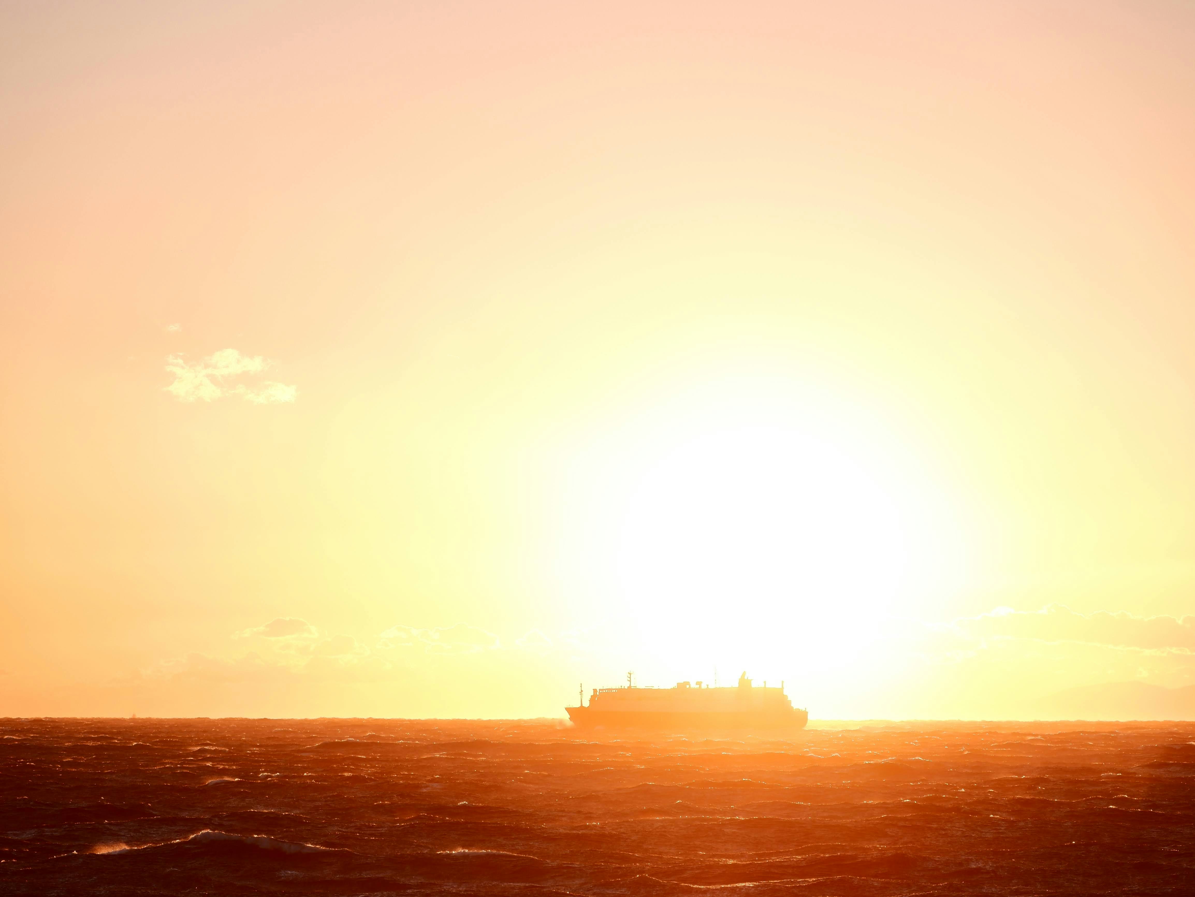 夕陽に照らされた海面と水平線の船影