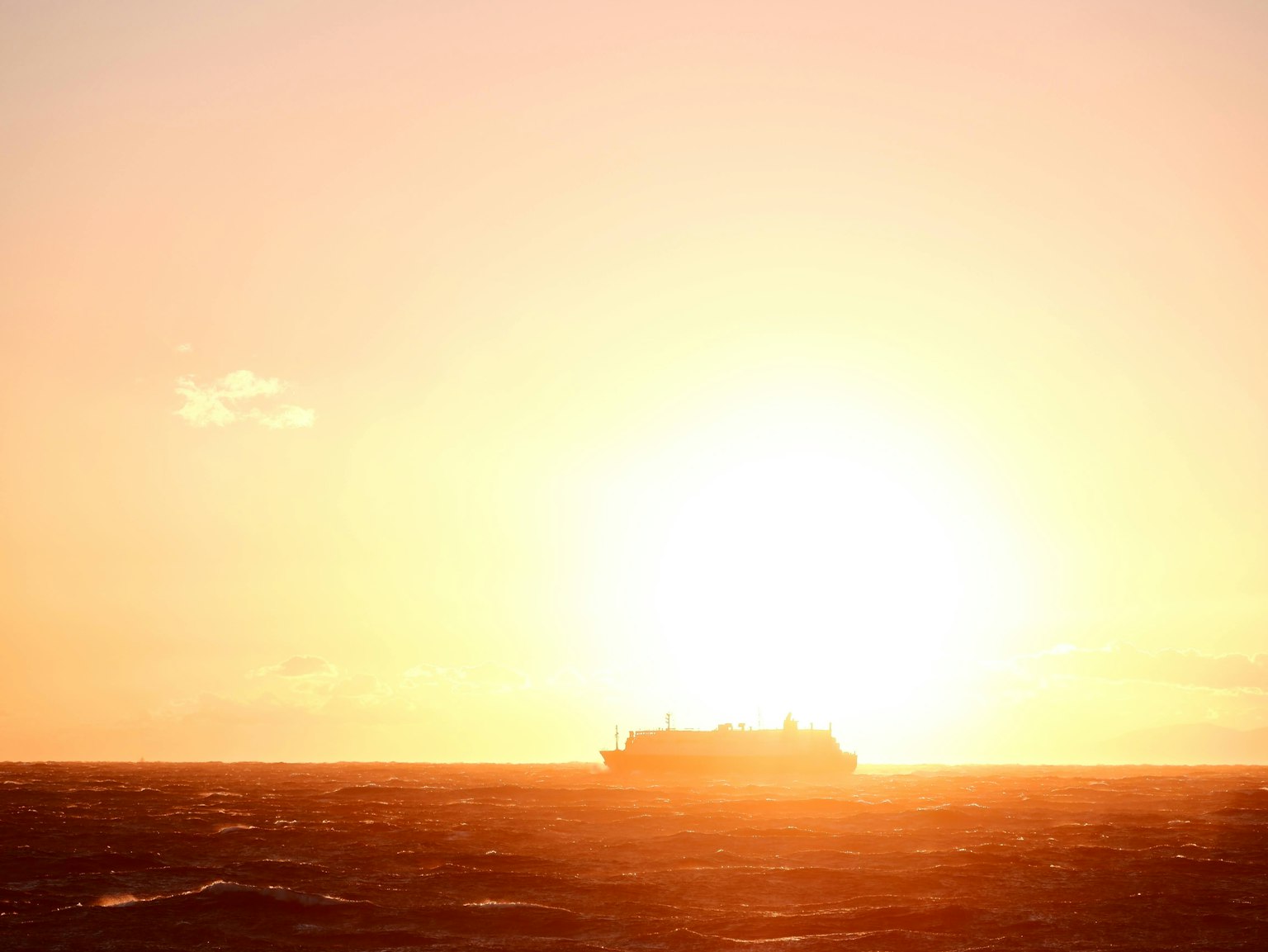 一艘船在夕阳下航行在海上