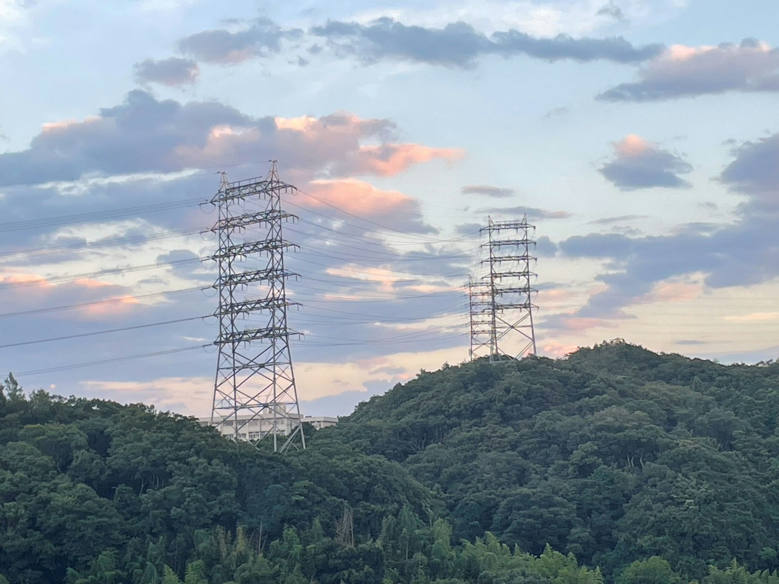 Líneas eléctricas de alta tensión que se elevan sobre las colinas bajo un hermoso cielo al atardecer