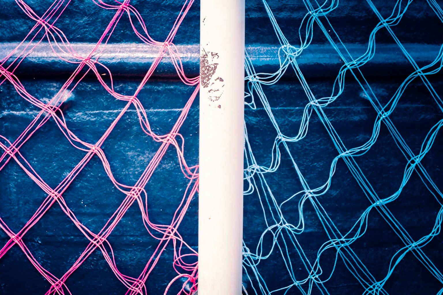 青とピンクのネットが交差する構図 白いポールが中央にある