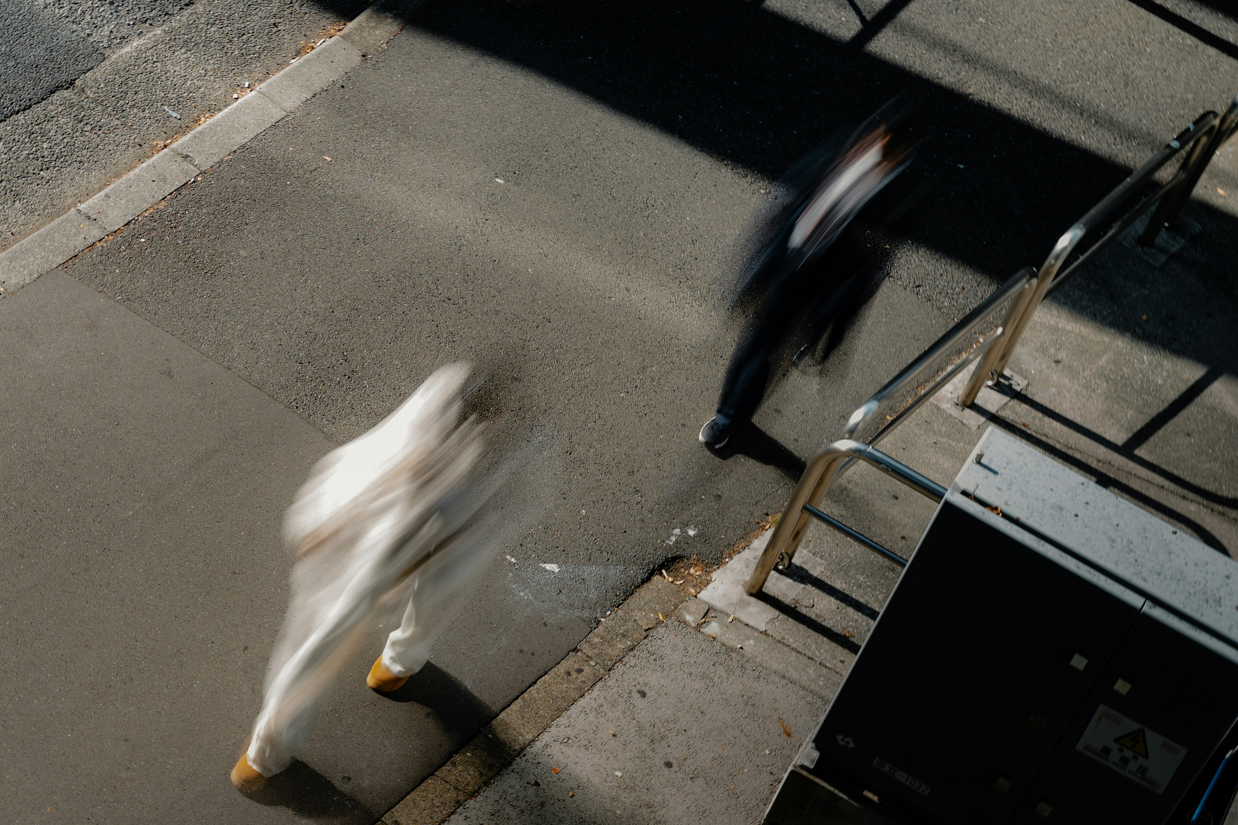 影と光のコントラストが強い路上の人物と階段