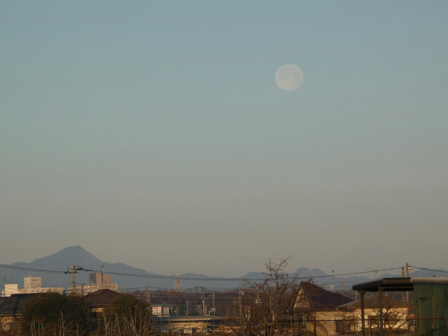Landscape with the moon in the blue sky and mountain silhouettes