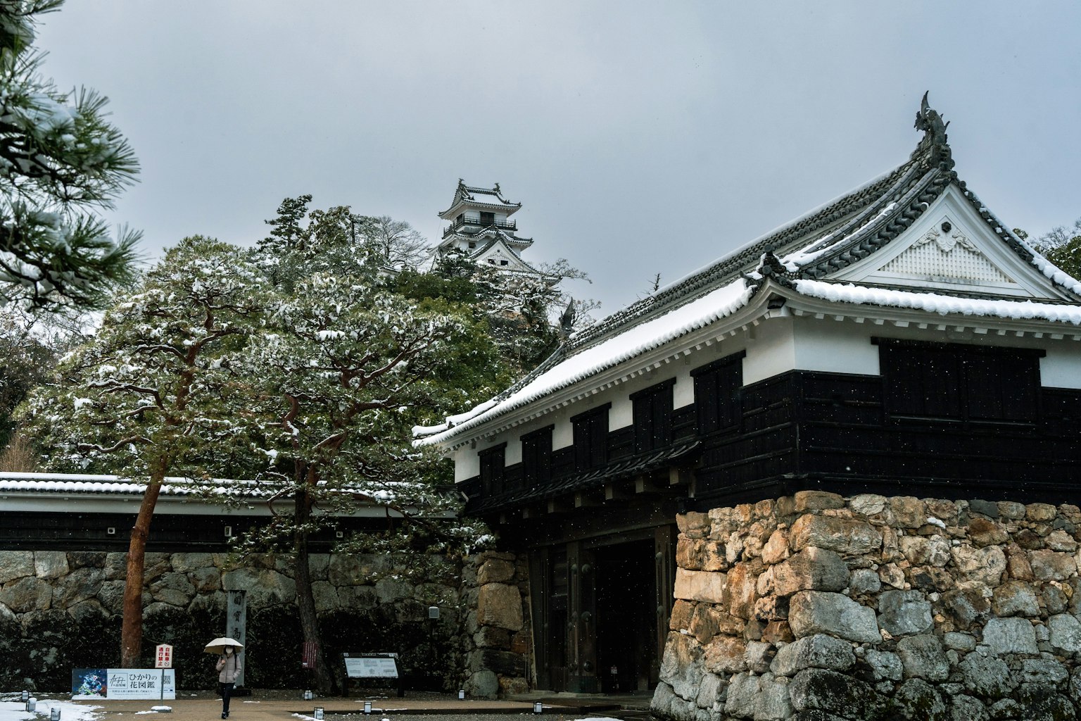 Bâtiment japonais traditionnel avec un toit couvert de neige et des arbres environnants