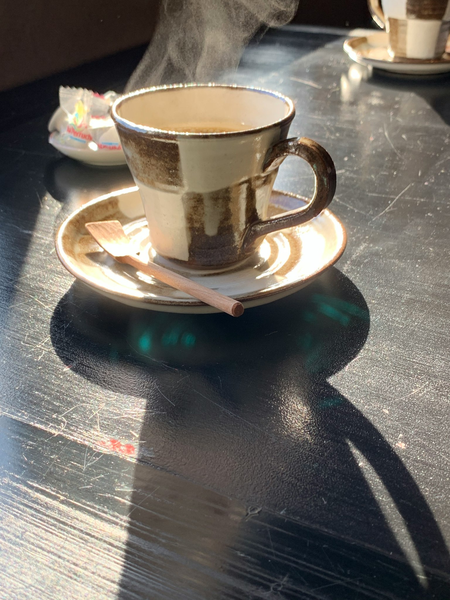 桌子上放著帶熱飲的陶瓷杯和碟子