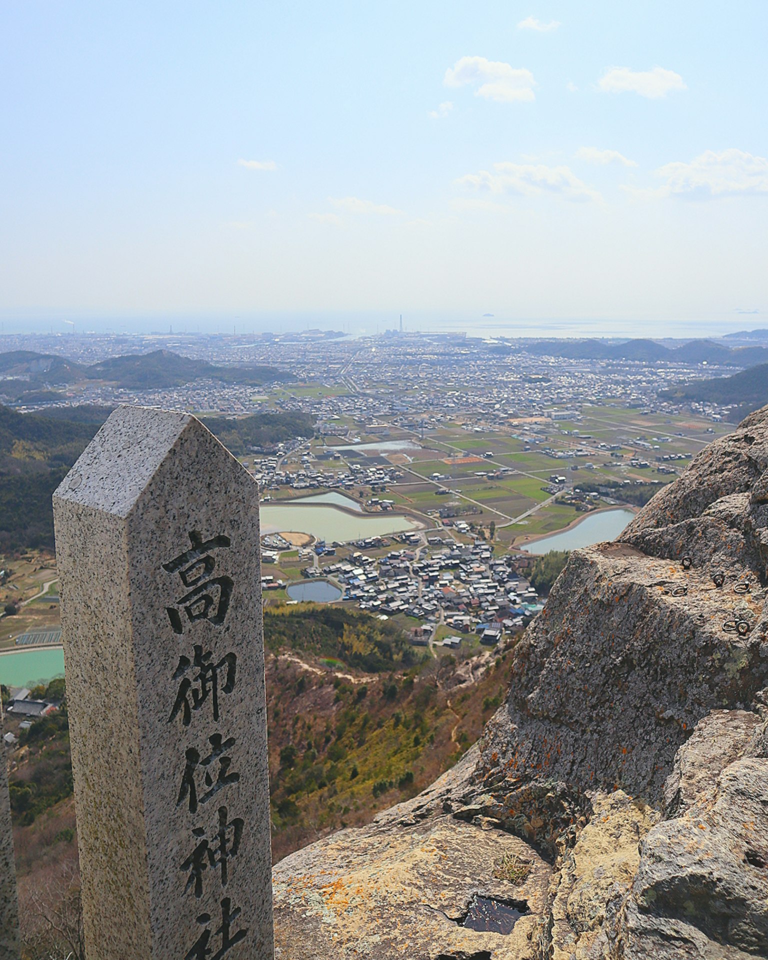 View from the summit featuring a stone marker of Takamikura Shrine and scenic landscape