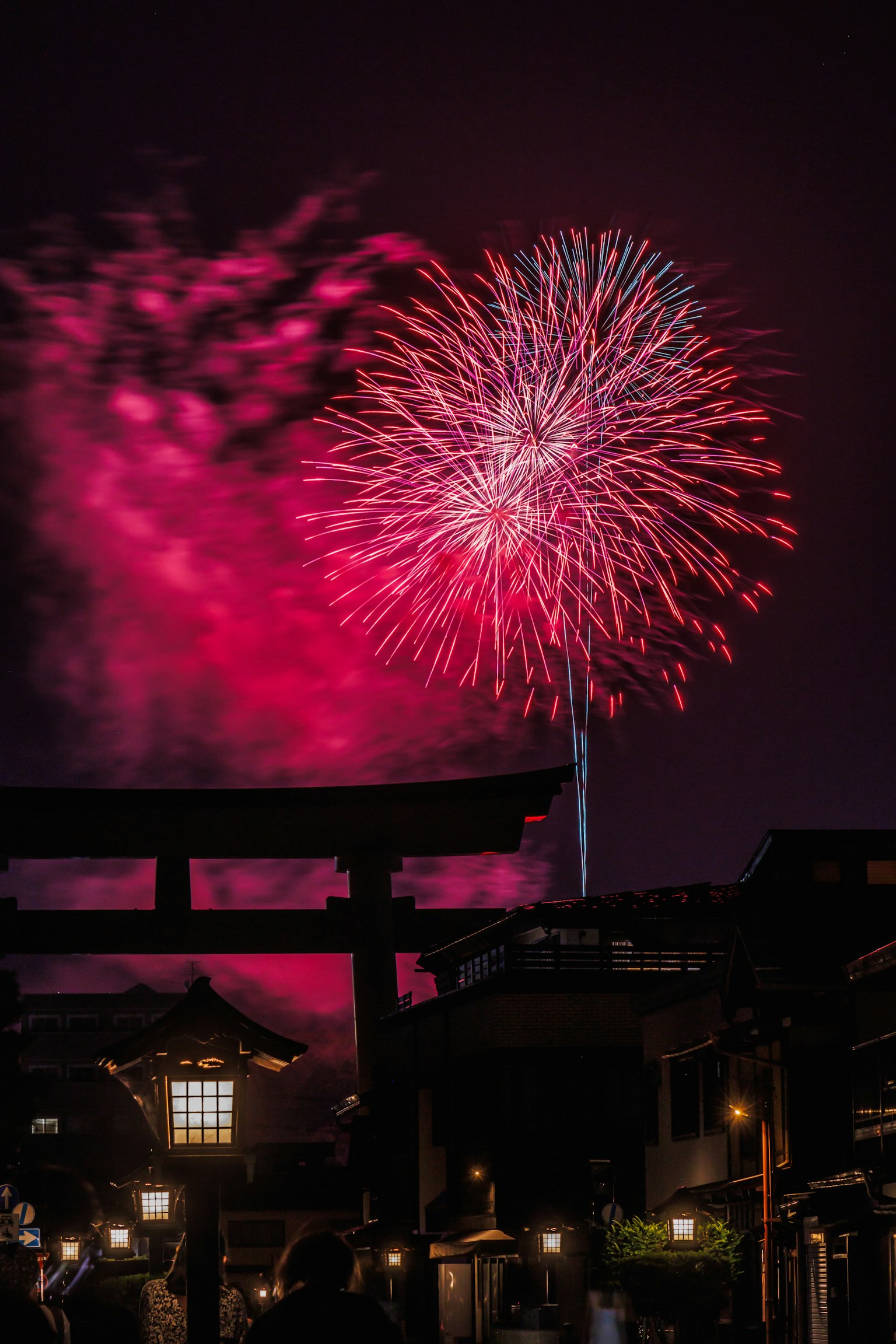 夜空中綻放的煙火與鳥居輪廓