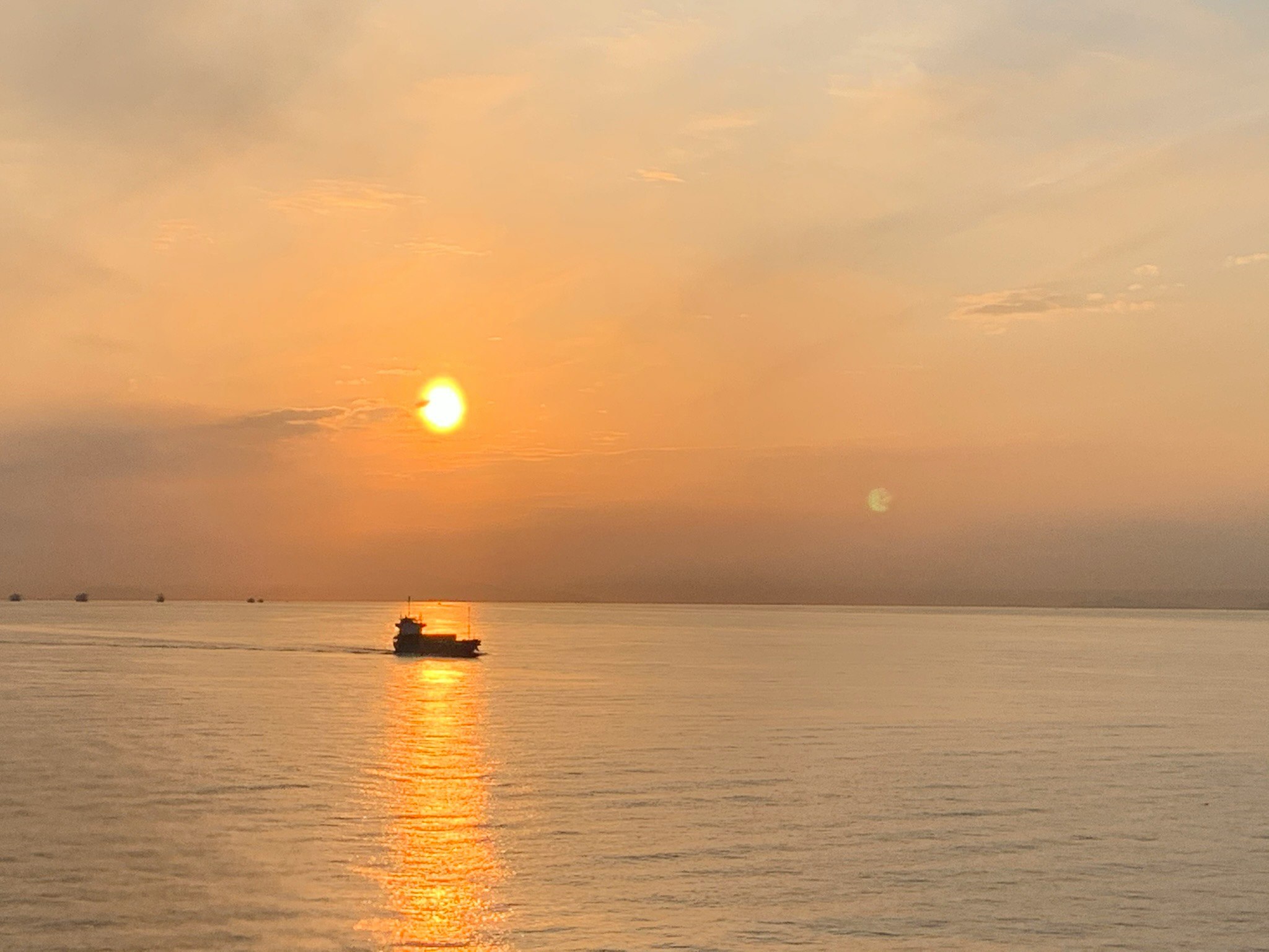 夕日に照らされる海面と小舟