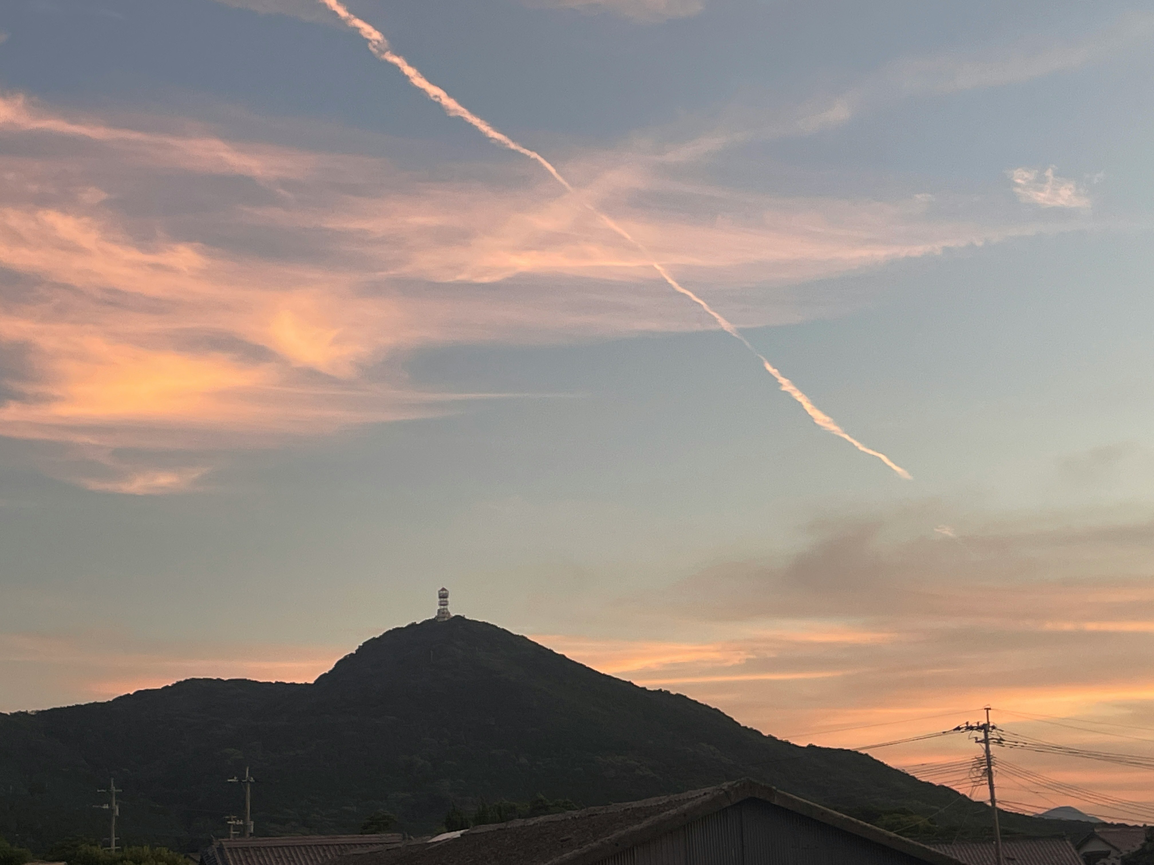 夕暮れの空と山のシルエット、飛行機雲のある風景