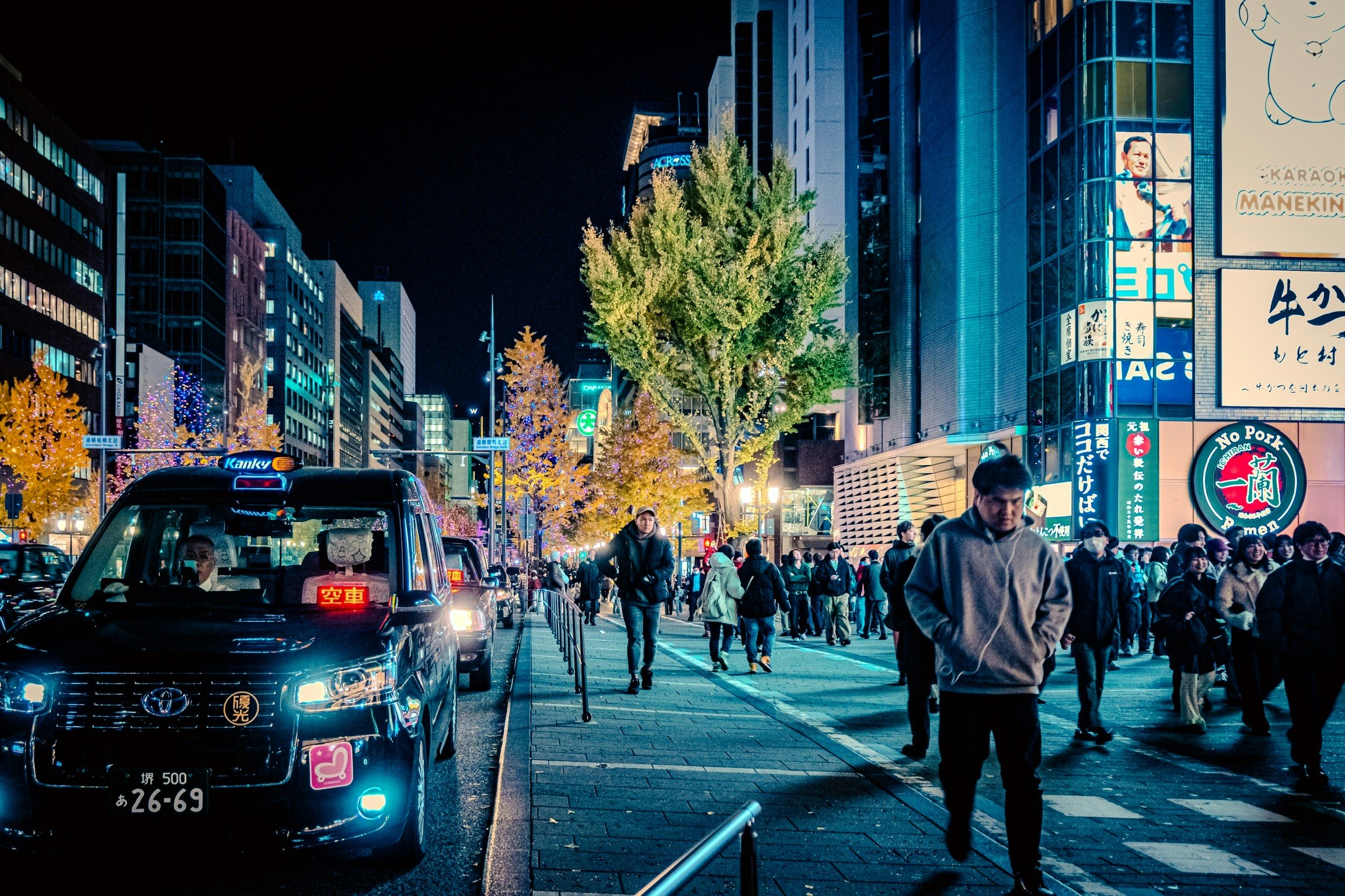 難波の夜のネオンが映える大通りを歩く人々と車