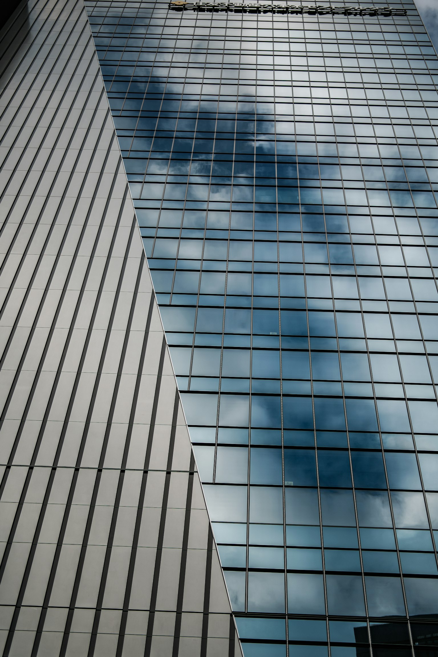 Schräges Glasgebäude mit Reflexionen und gestreifter Fassade