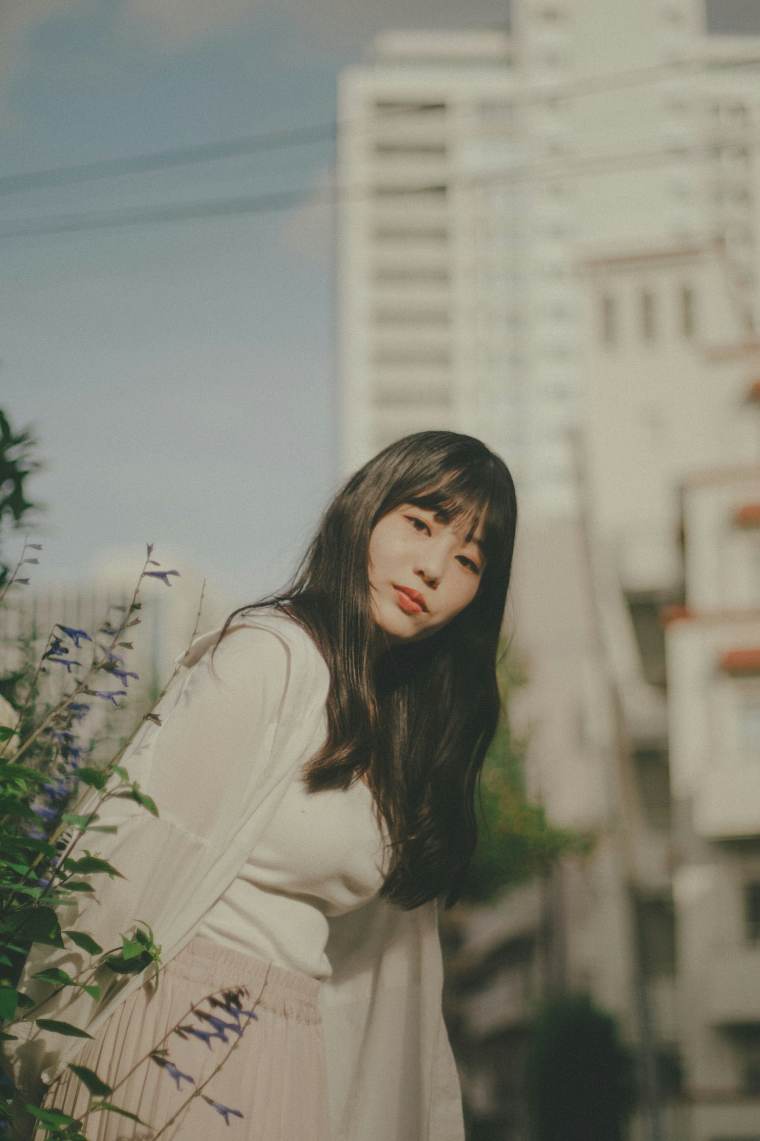 여성이 도시 배경에 꽃에 기대고 있는 모습