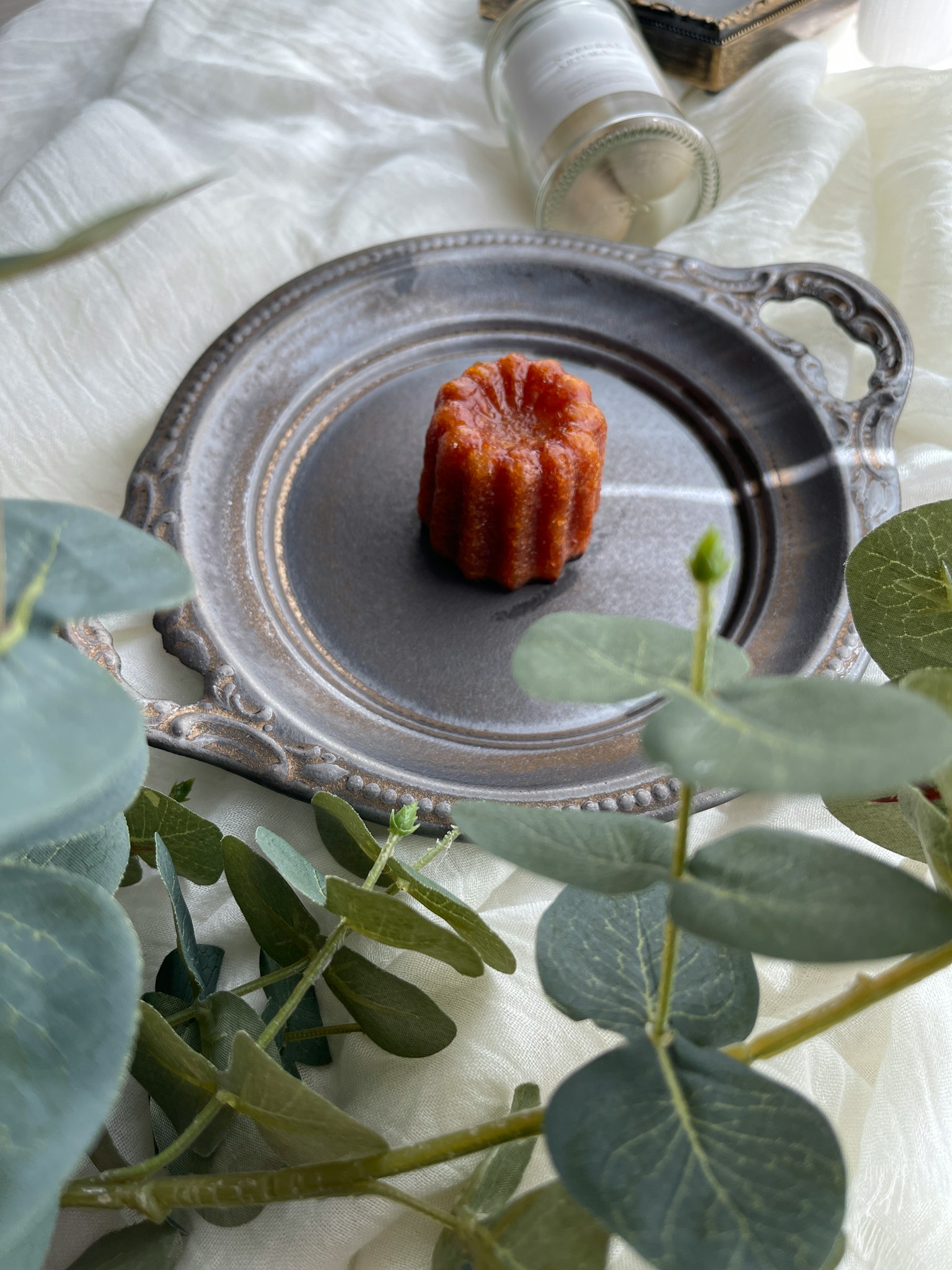 Canelé sur un plateau argenté avec des feuilles d'eucalyptus