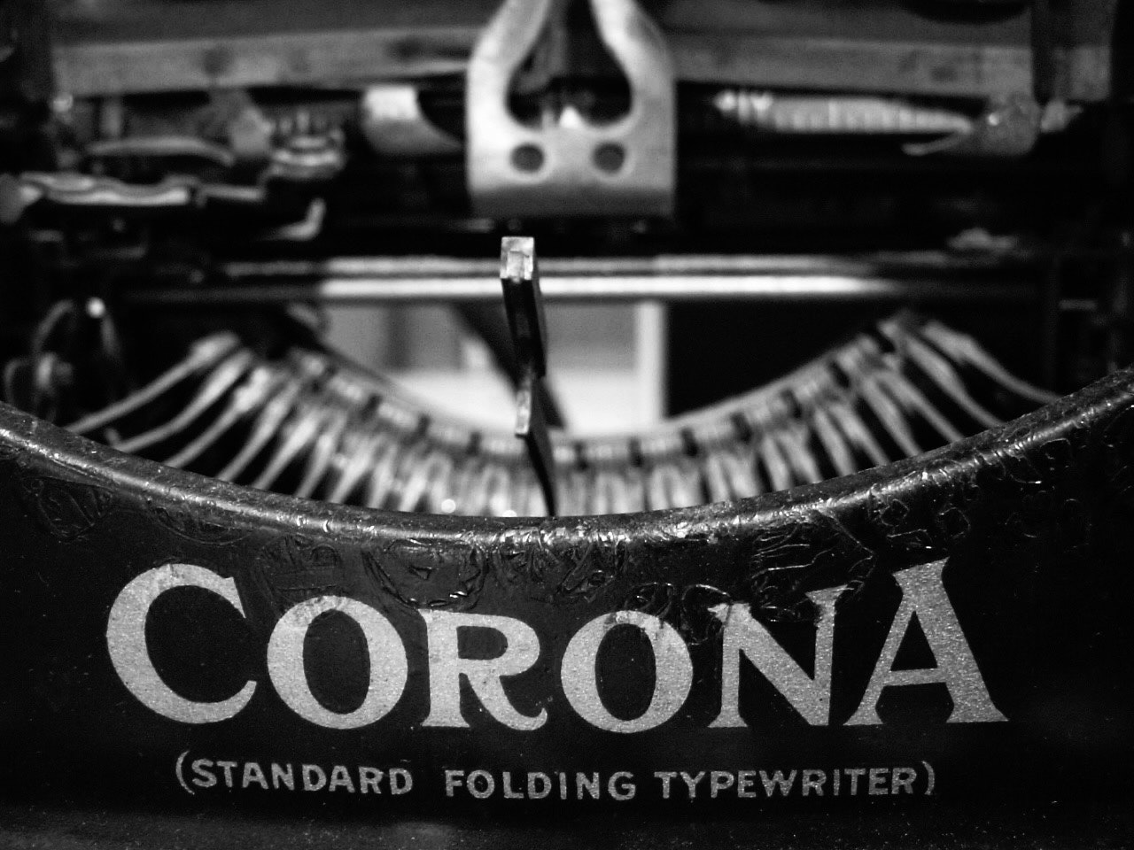 「CORONA」刻印の折りたたみ式タイプライターのあるモノクロの作業机